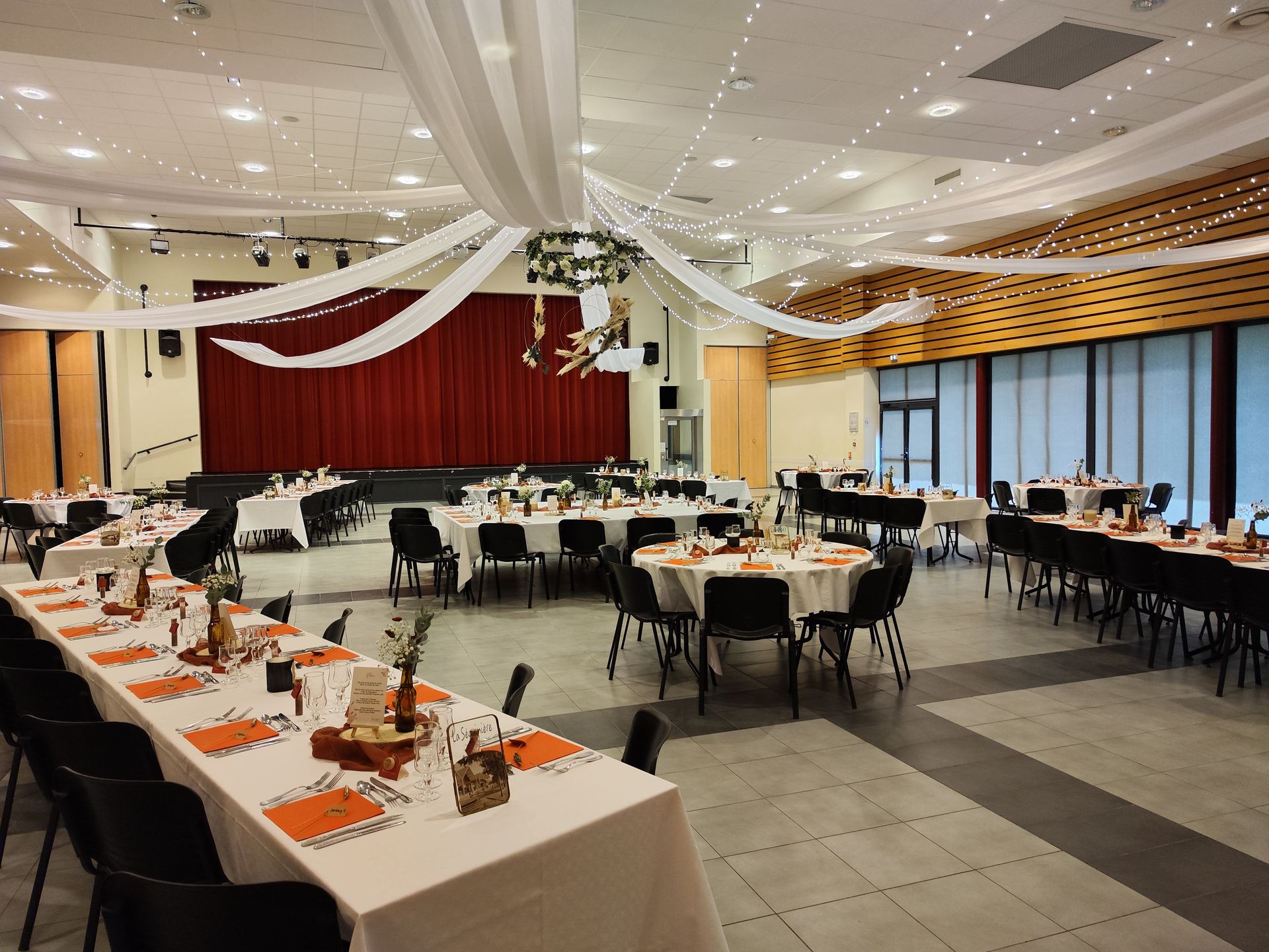Mariage Espace Galerne plafond tentures blanche leds couronne de feuillage pampas table blanche serviette orange rondin en bois tissu terracotta
