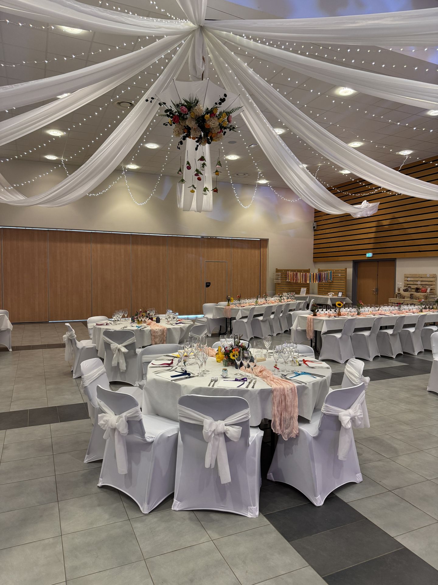 plafond en soleil drapé blanc led et composition florales table blanche et coloré fleurs