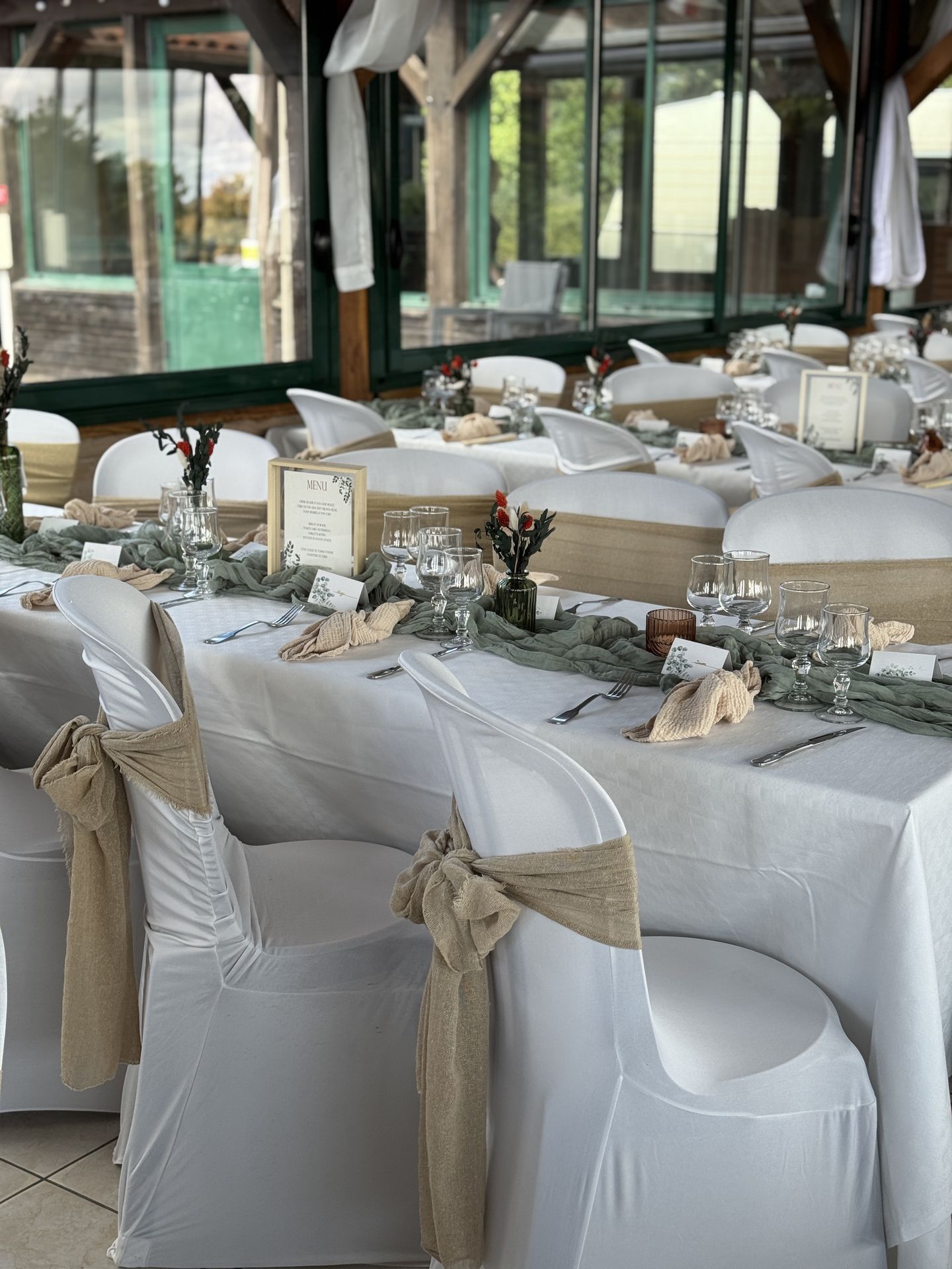 salle intérieur drapé blanc nœud de chaise sable chemin de table vert sauge vase fleurs sèches
