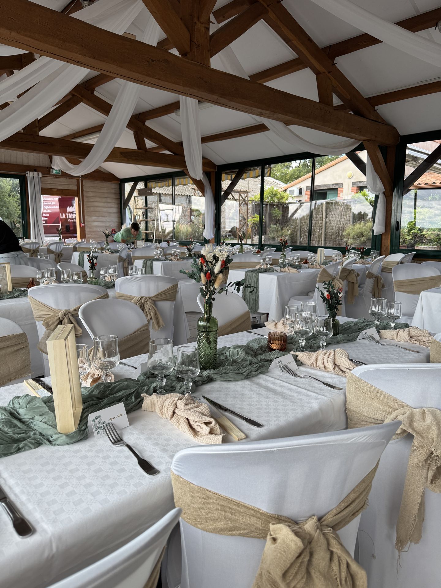 salle intérieur drapé blanc nœud de chaise sable chemin de table vert sauge vase fleurs sèches