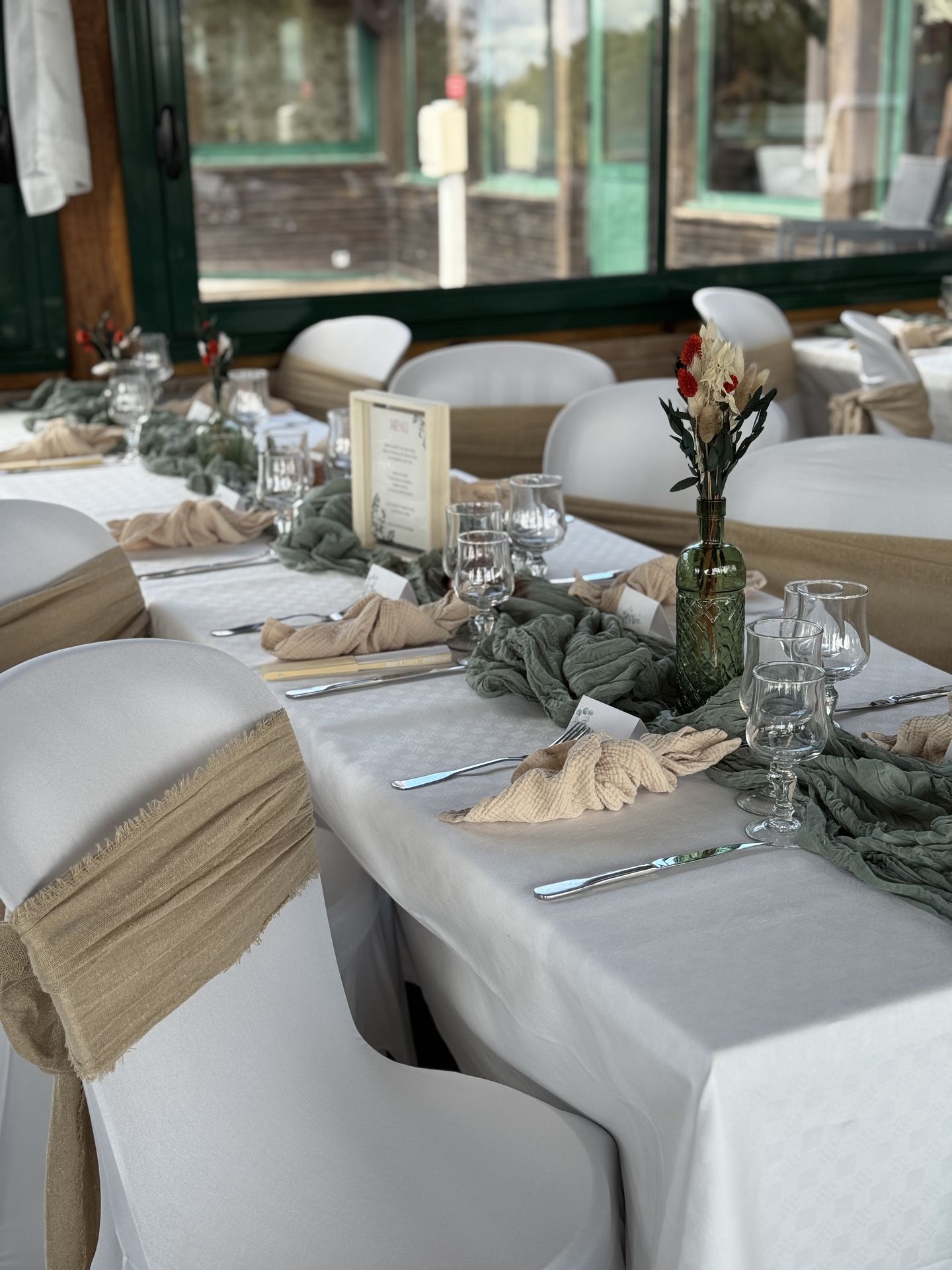 salle intérieur drapé blanc nœud de chaise sable chemin de table vert sauge vase fleurs sèches