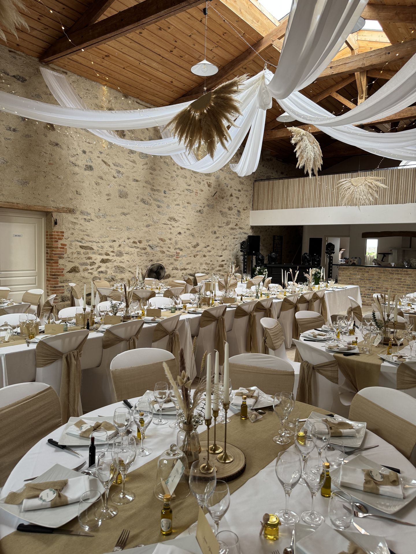 salle intérieur tentures blanche pampas soleil table blanche et sable nœud de chaise rondin de bois bougeoir doré cadeau invités personnalisé