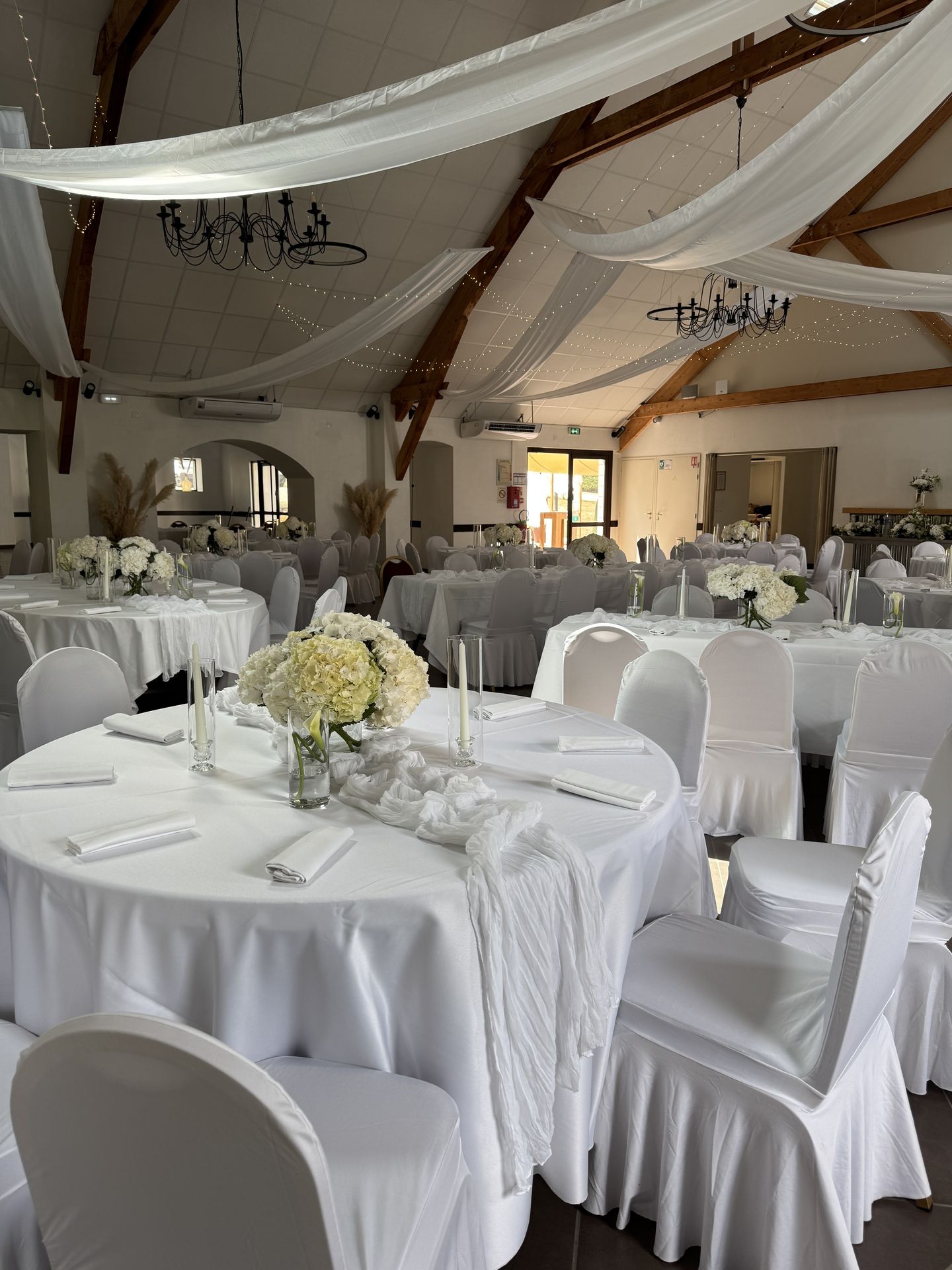salle intérieur tentures croisés blanches et led lumineuse table blanche et composition florale bougie