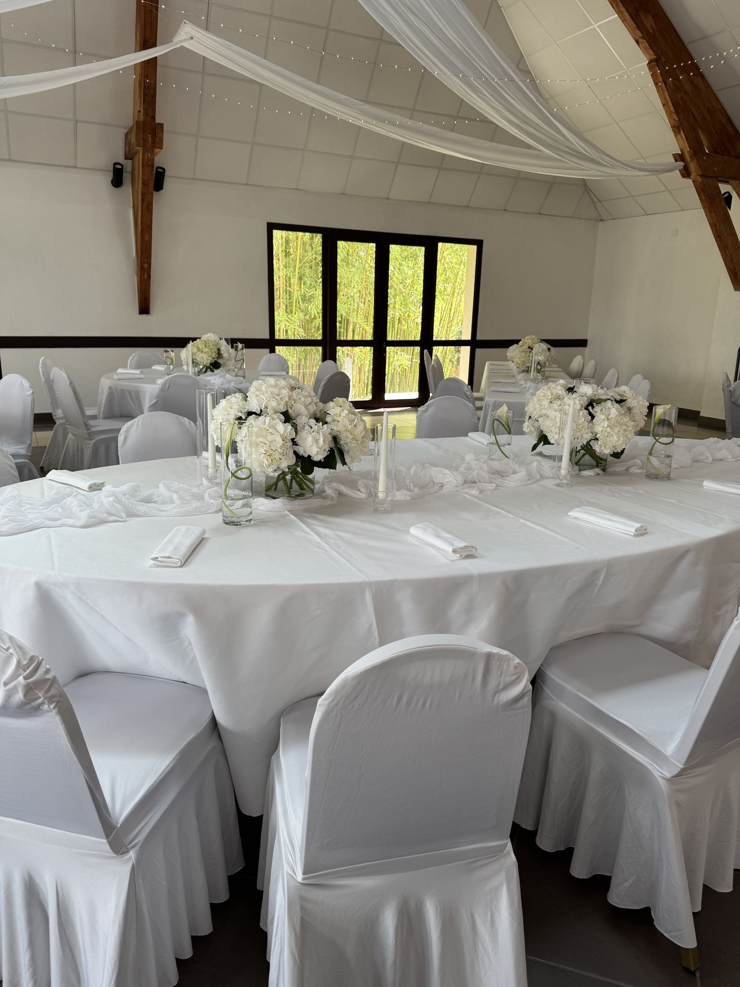 salle intérieur tentures croisés blanches et led lumineuse table blanche et composition florale bougie