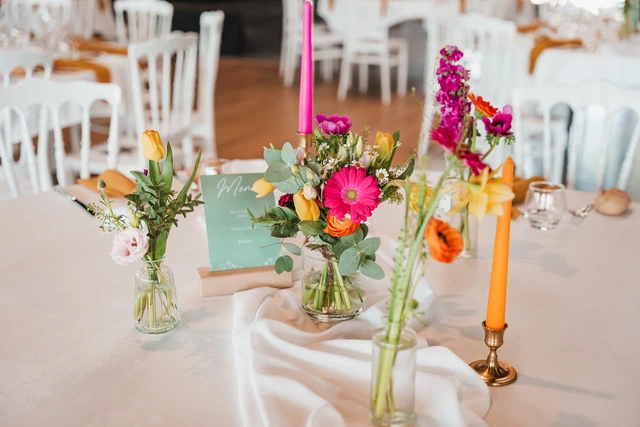 Mariage Domaine de la Sapinière chemin de table blanc compositions florales rose orange et blanche dans des vases transparents bougies de couleurs