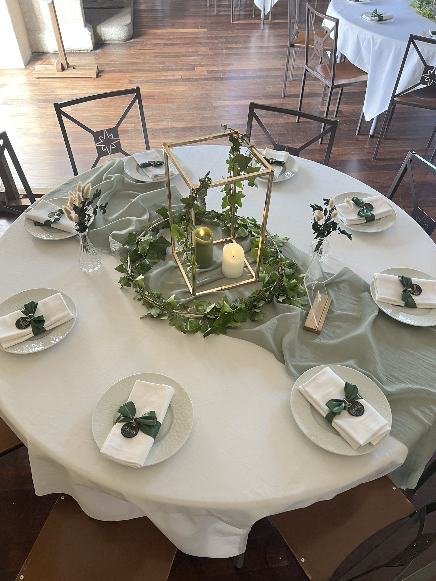 Mariage La belle étoile salle intérieure table blanche chemin de table vert sauge et composition de feuillage vert et bougies
