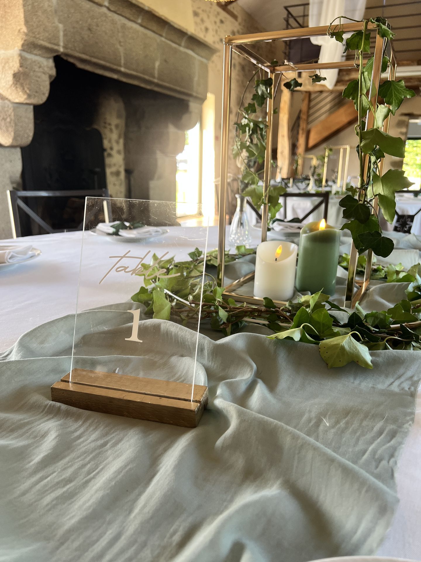Mariage La belle étoile salle intérieur centre de table cadre doré feuillage bougie verte et blanche nom de table plexis blanc sur socle