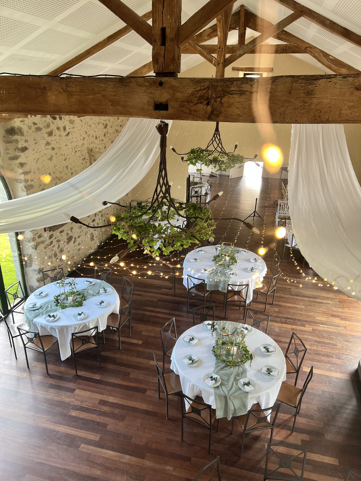 Mariage La belle étoile salle intérieure table blanche chemin de table vert sauge et composition de feuillage vert et bougies