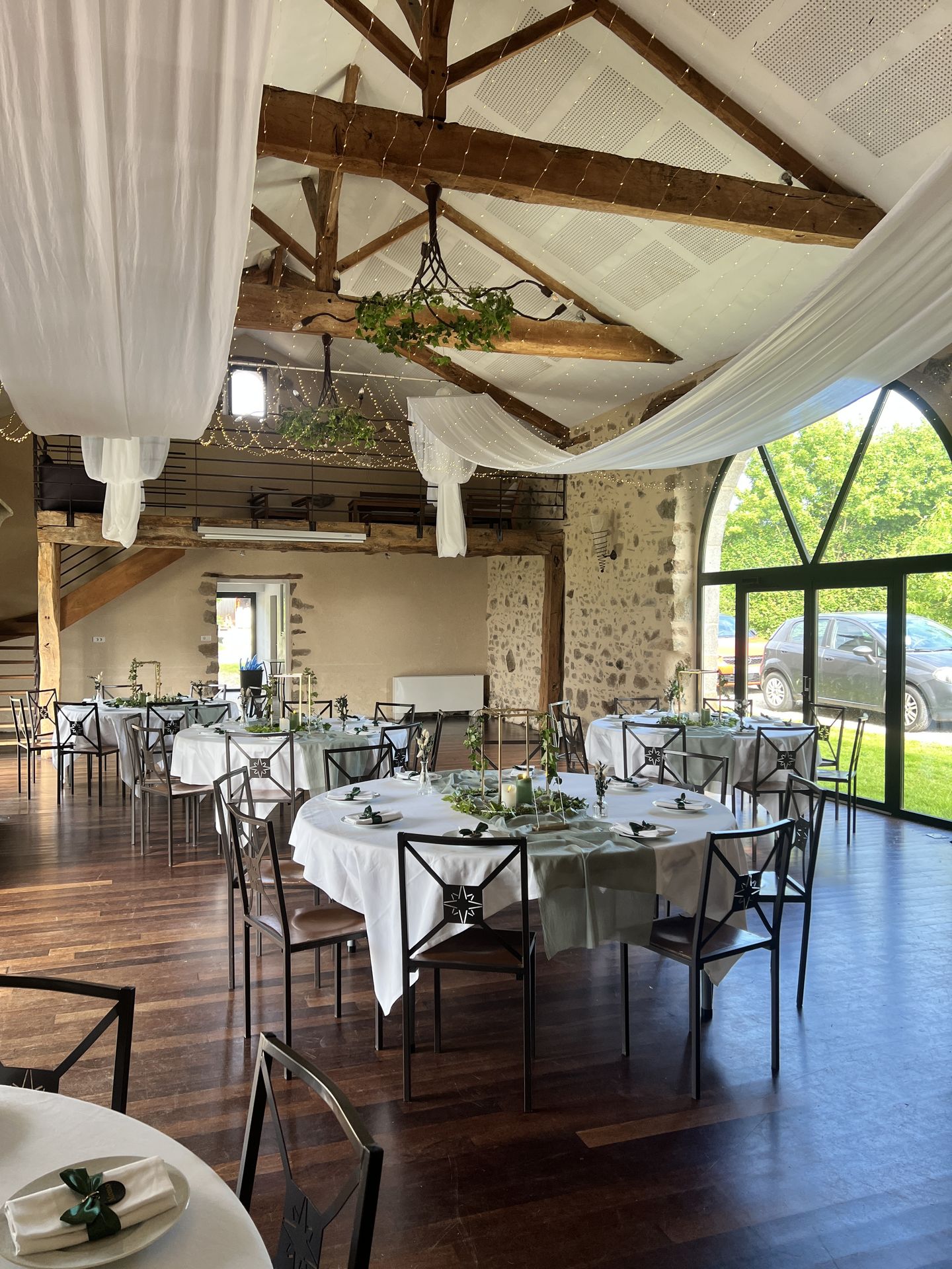 Mariage La belle étoile salle intérieure table blanche chemin de table vert sauge et composition de feuillage vert et bougies