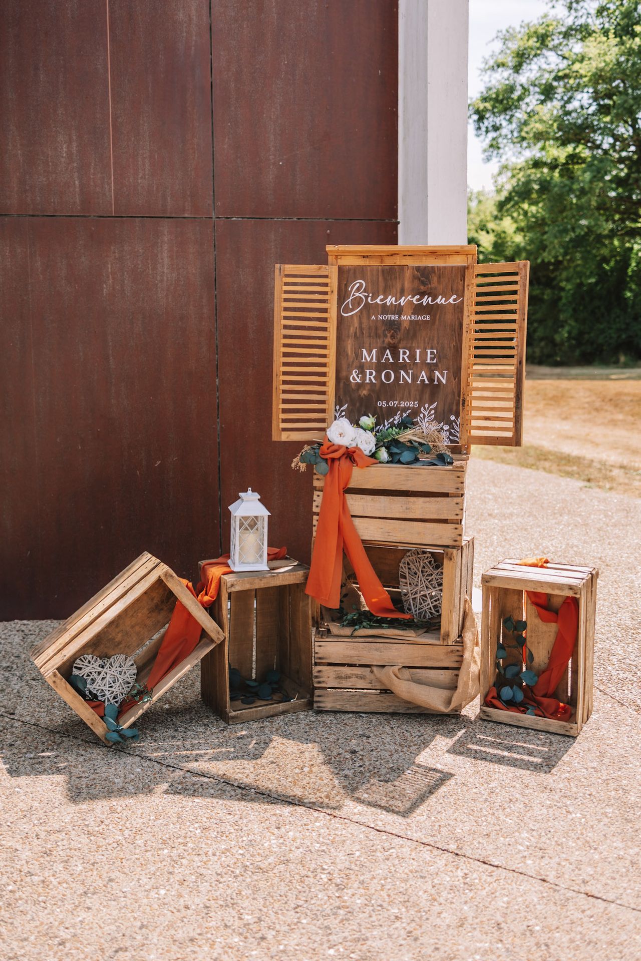 Mariage La Thèvinière panneau de bienvenue caisse de pommes tissu terracotta fleurs blanches et feuillage lanterne