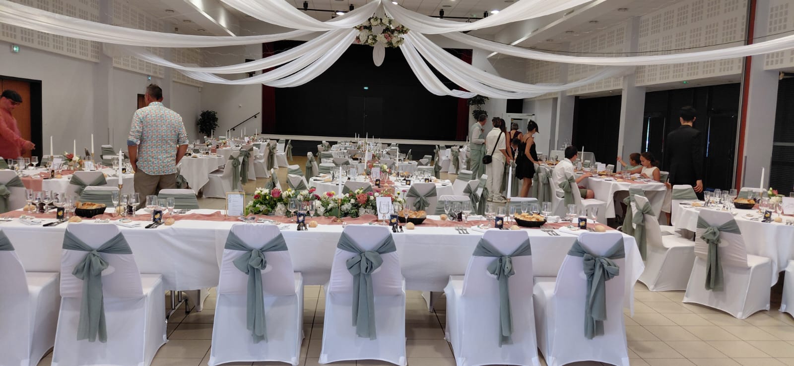 Mariage La Thèvinière tenutres blanches et leds courone de fleurs blanches et roses cercle logo des mariés table blanches noeuds de chaises vert sauges et chemin de table vieux rose