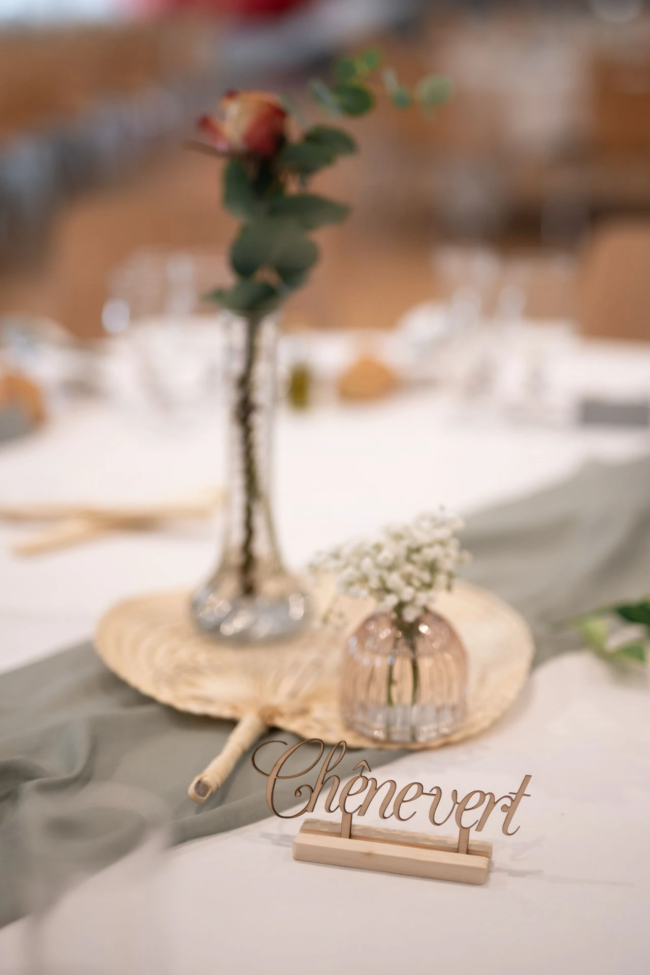 Mariage Les Landebaudières tables blanches chemin de table vert sauge centre de table naturel vase feuillage serviette vert sauge nom de table en bois