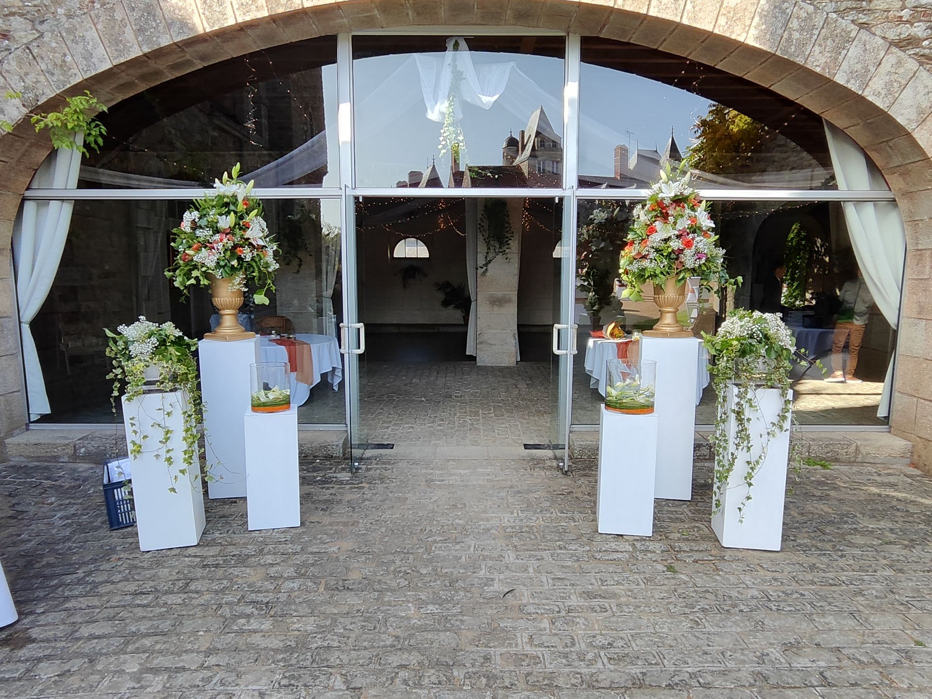 ion Mariage Château de la Bretonnière entrée de salle composition fleurales socle blanc