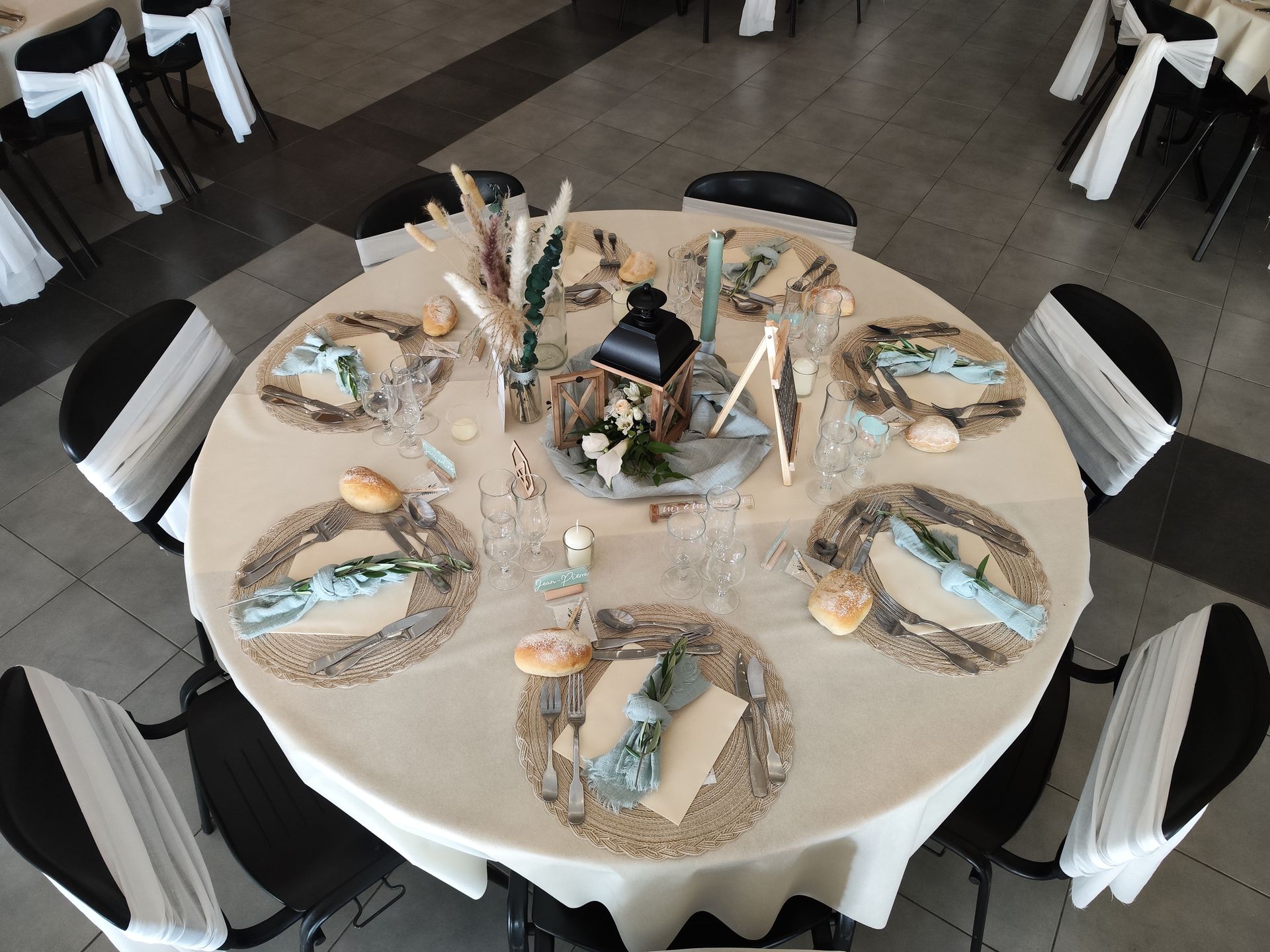 Mariage Espace Galerne tables blanches neouds de chaises centre de tables vert sauge rondin bois lanterne bois vase composition florales pampas