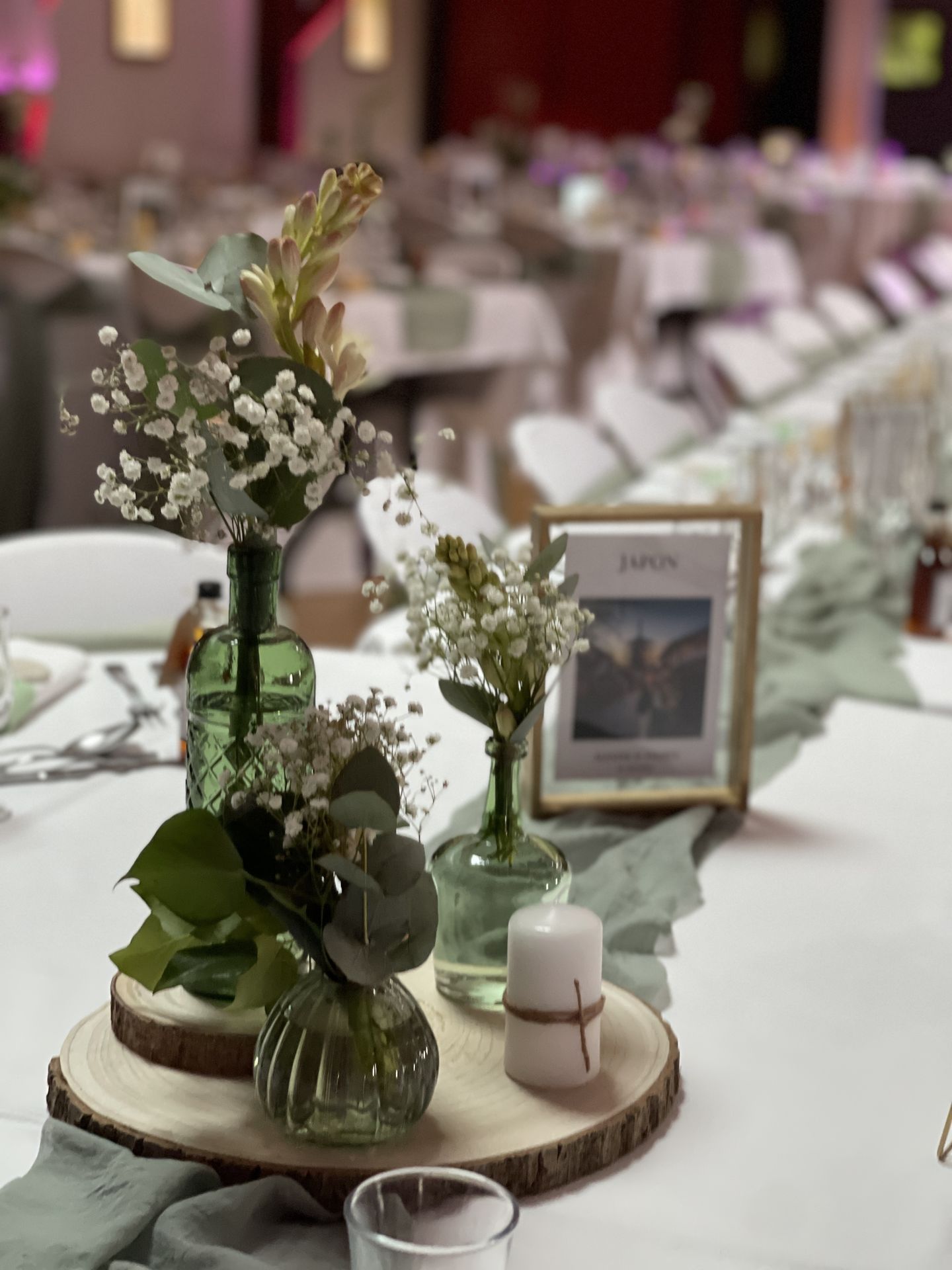 Mariage Salle de la Goubaudière salle intérieure tables blanches centre de table rondin bois vase vert et feuillage bougies