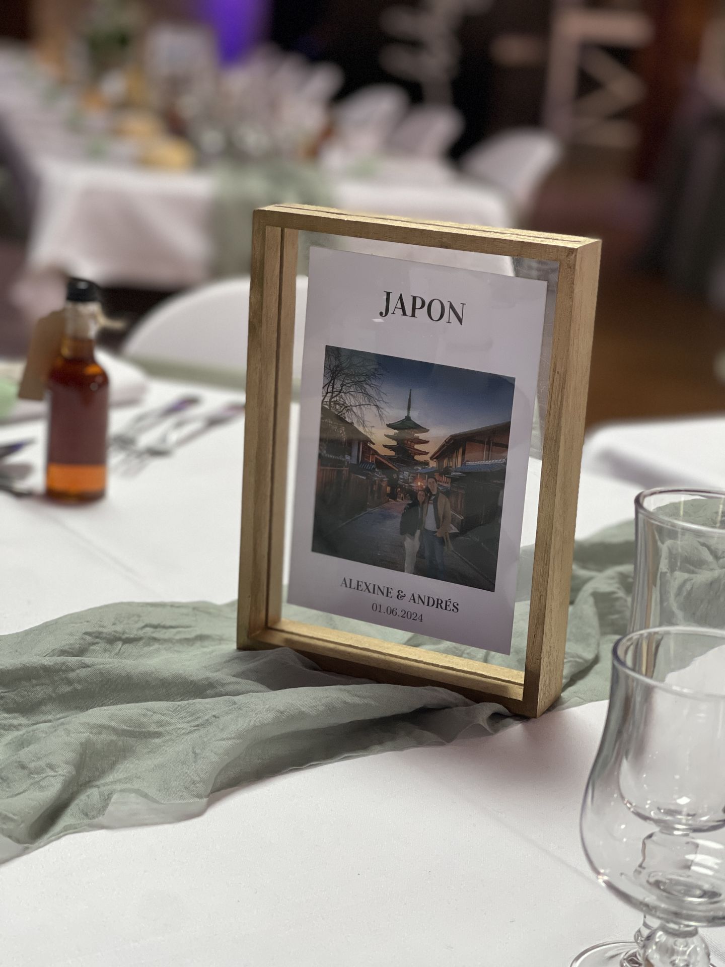 Mariage Salle de la Goubaudière salle intérieure tables blanches chemin de table vert sauge cadre photo voyage nom de table bois naturel
