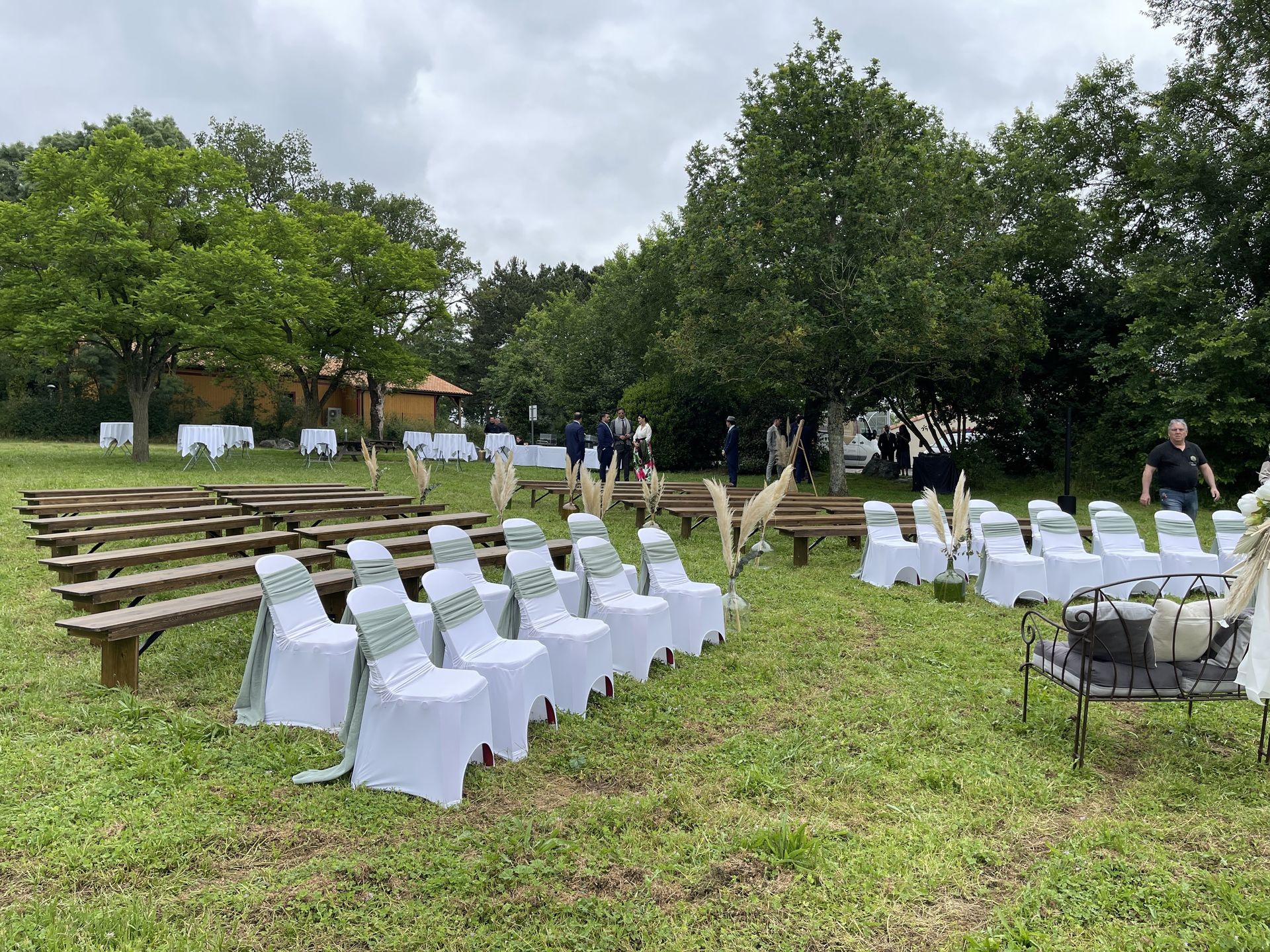 Mariage Salle de la Goubaudière cérémonie laique extérieure vase couleur pamaps arche tentures blanc chaises blanches noeuds vert sauge