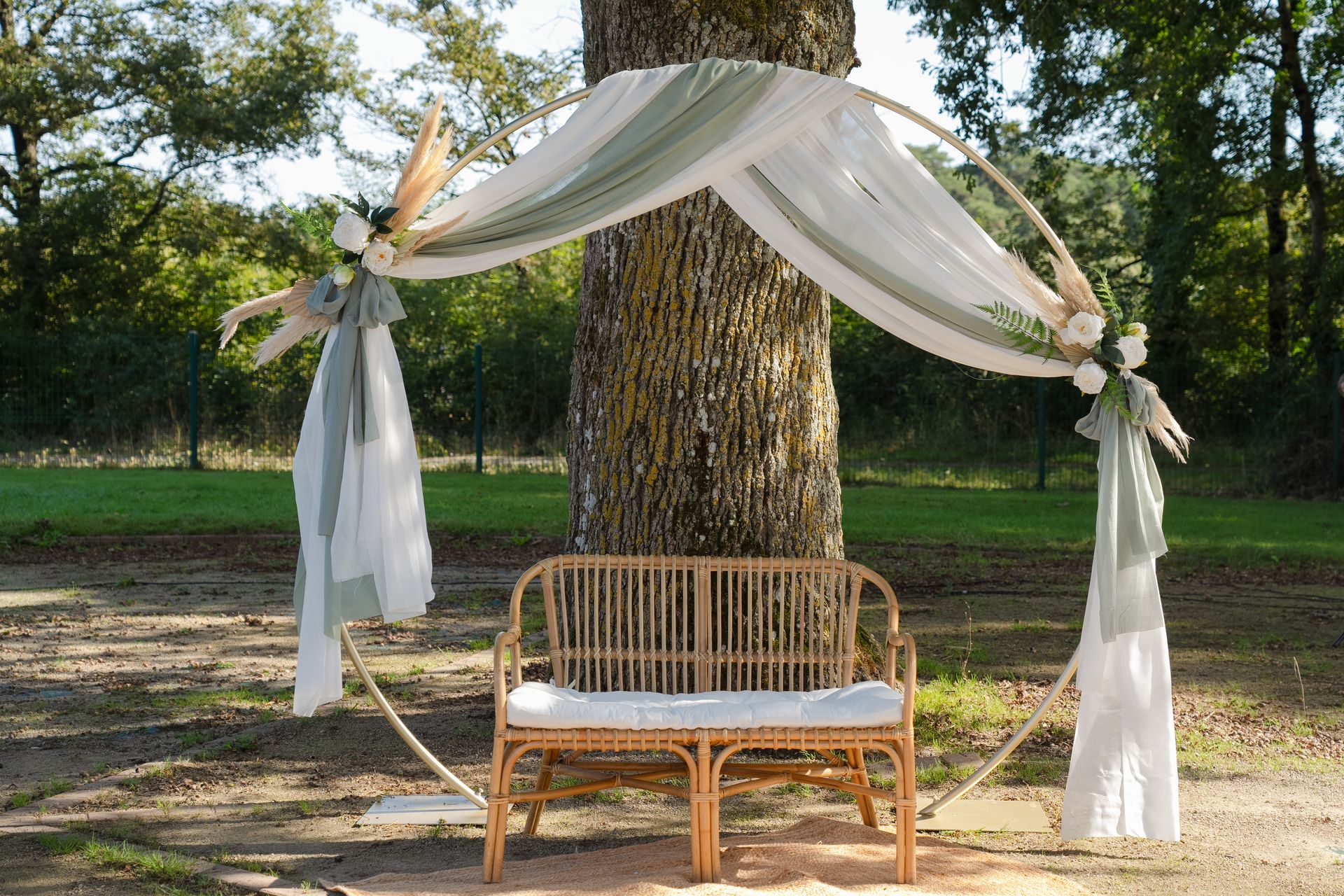 Mariage la thévinière arche ronde tissu blanche et vert sauge banc bois et pampas