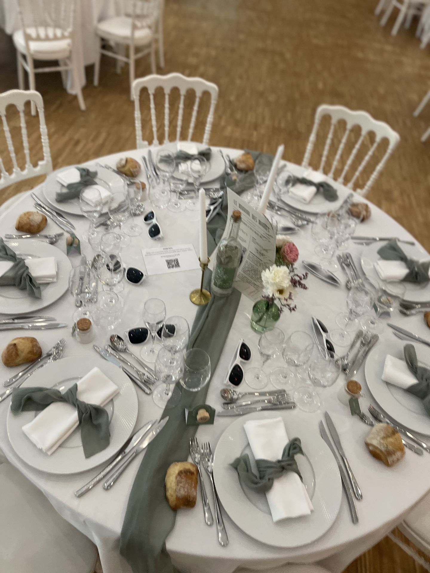 Mariage les Landebaudières tables blanches chemin vert sauge serviette blanche et noeuds vert sauge bouteille en verre menu bougies blanches