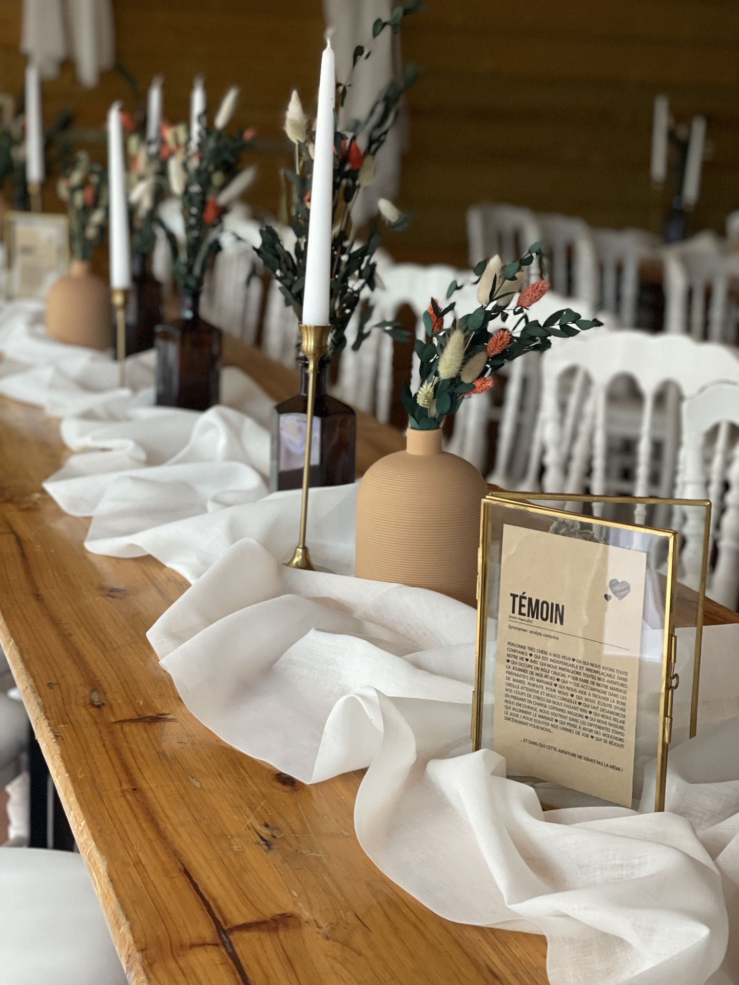 Mariage La Rabotière table bois naturel chemin de table blanc vase matte naturel bougie blanche fleurs sèches chatons cadre doré