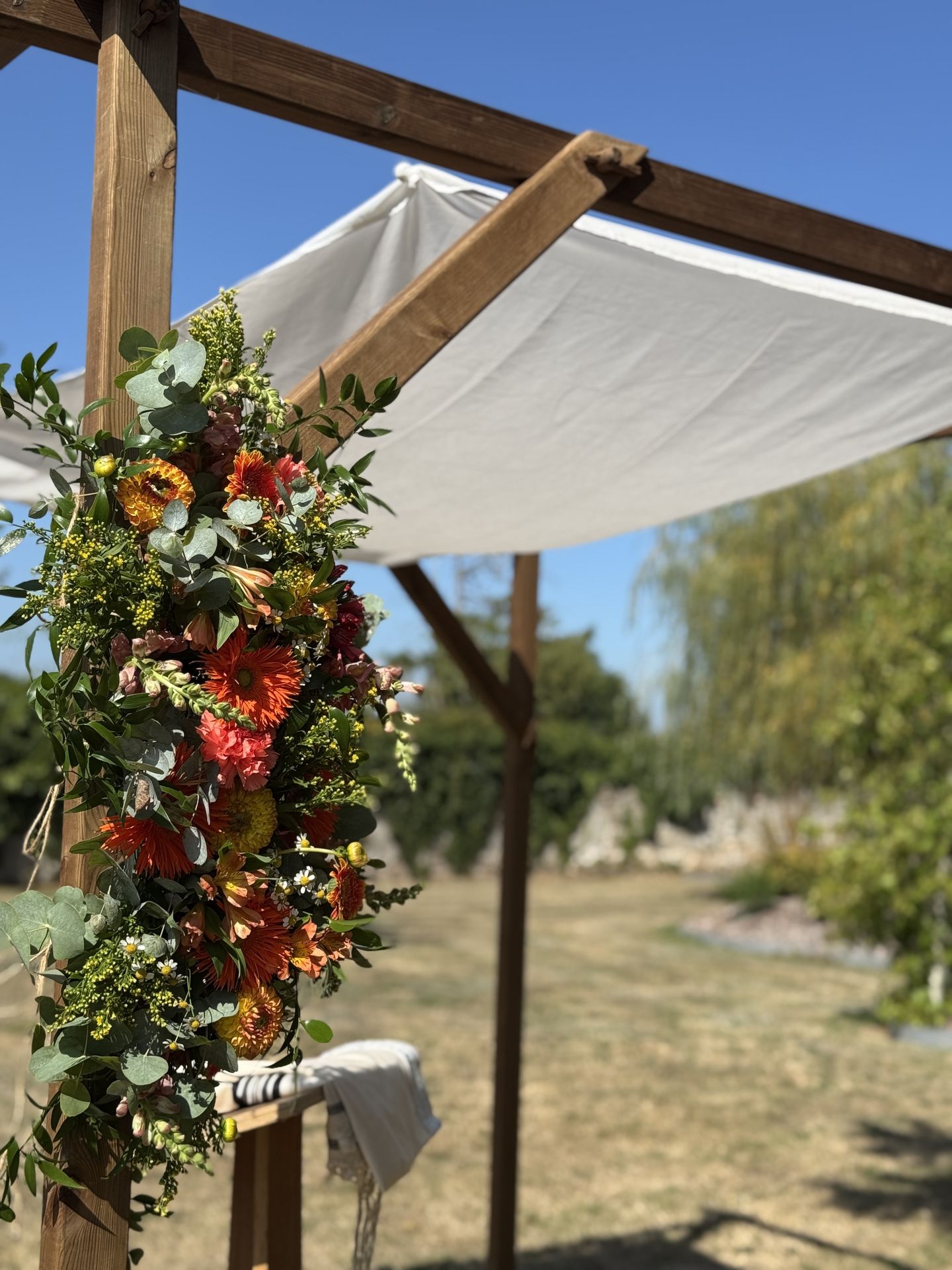 Mariage la Barbinière arche tissu blanc pupitre composition floales orange feuillage