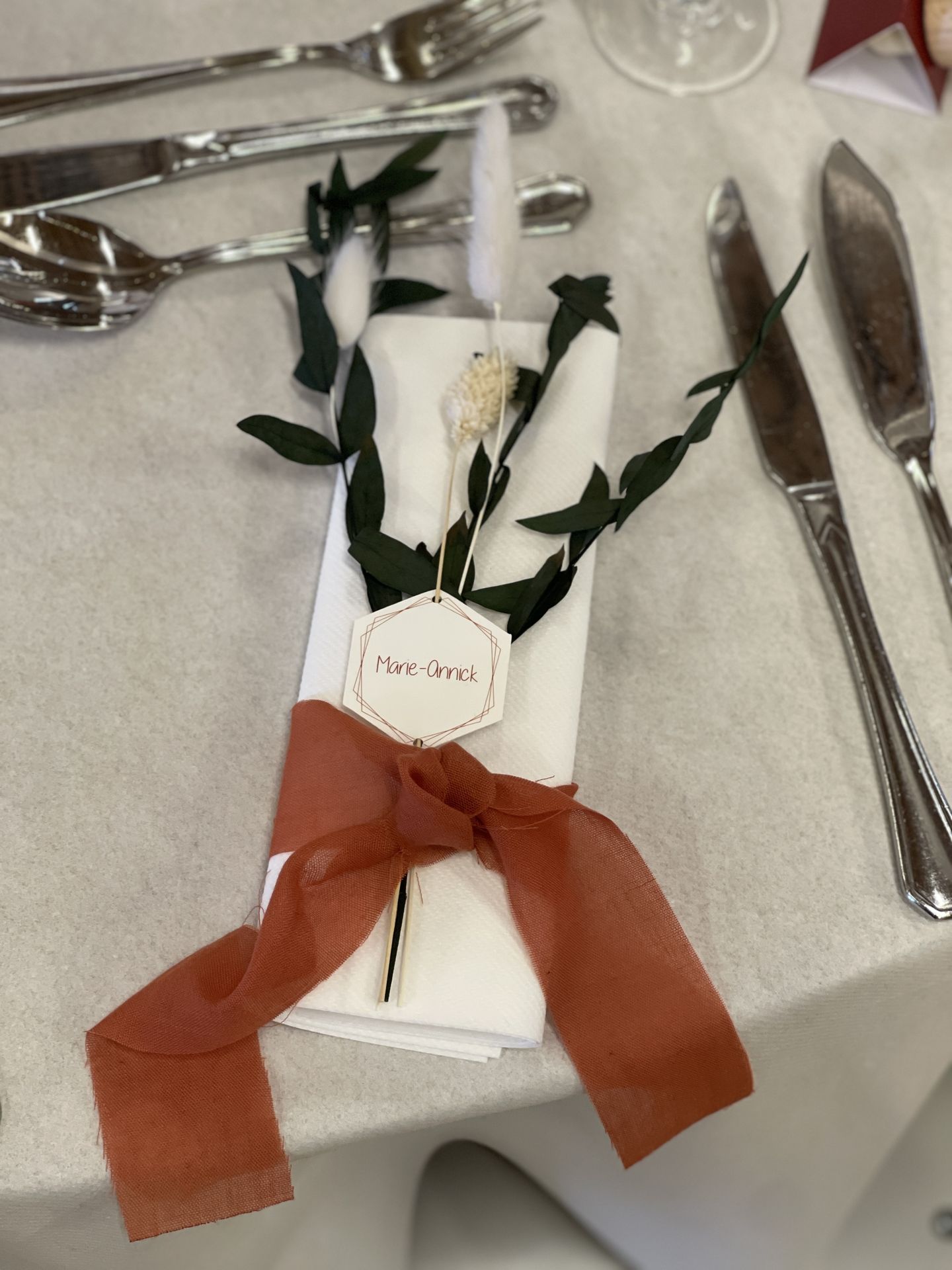 Mariage La Prairie serviette blanche noeud terracotta feuillage chaton blanc marque place