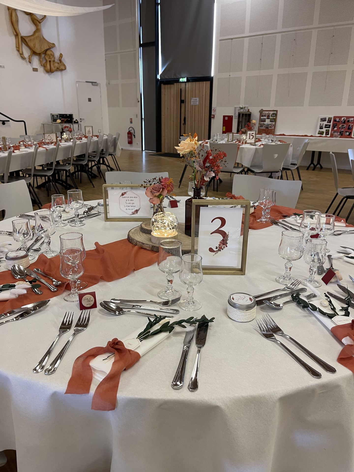 Mariage La Prairie table blanche chemin de table terracotta menu cadre en bois centre de table rondin en bois vase leds fleurs terracotta