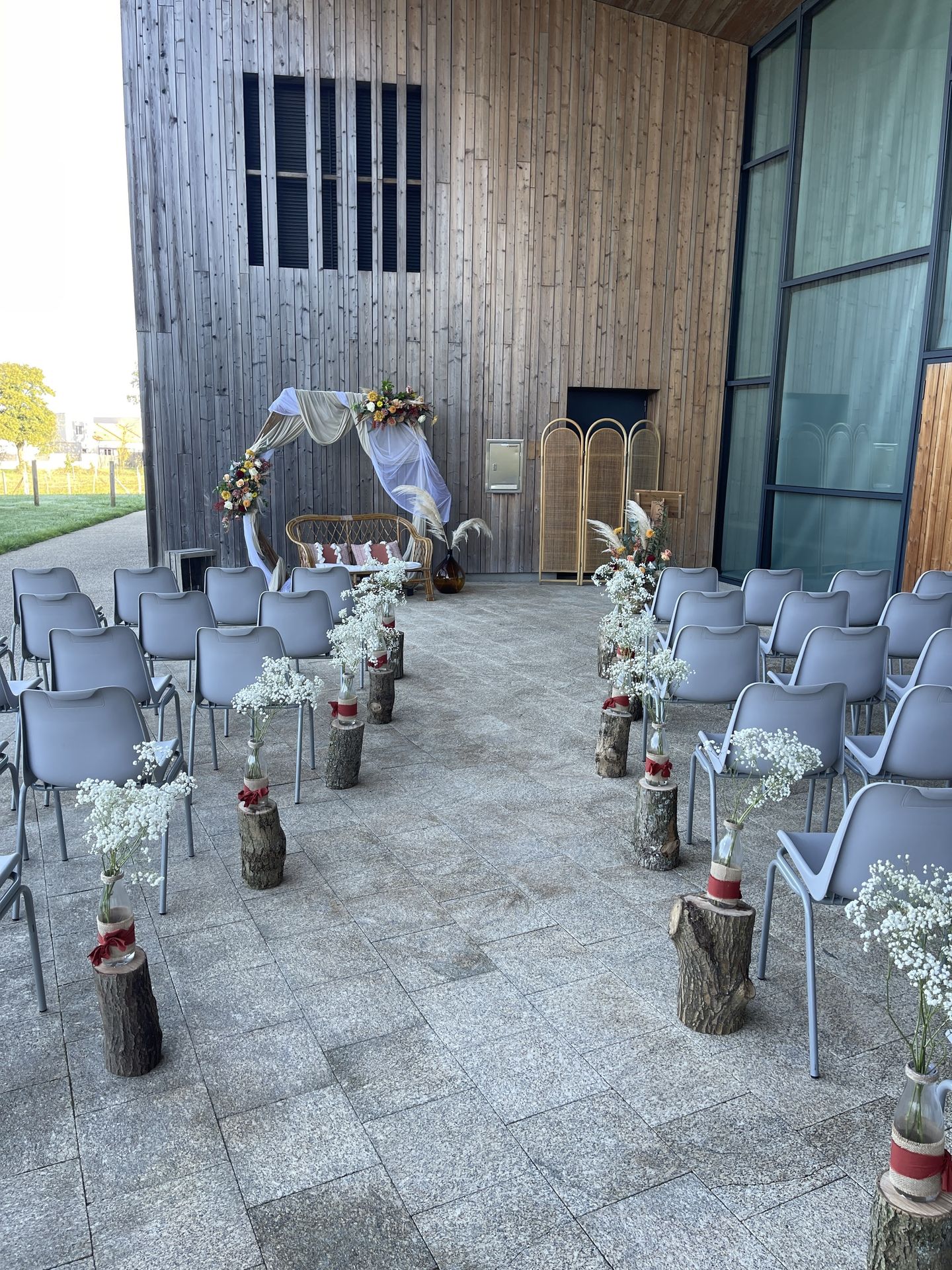 Mariage La Prairie cérémonie laique arche tissu blanc et sable composition florales canapé bois