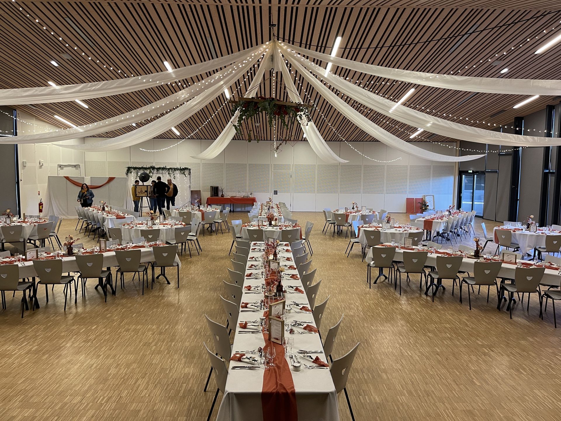 Mariage La Prairie slle intérieur plafond tentures blanches leds structure bois et feuillage table blanches chemin de table terracotta