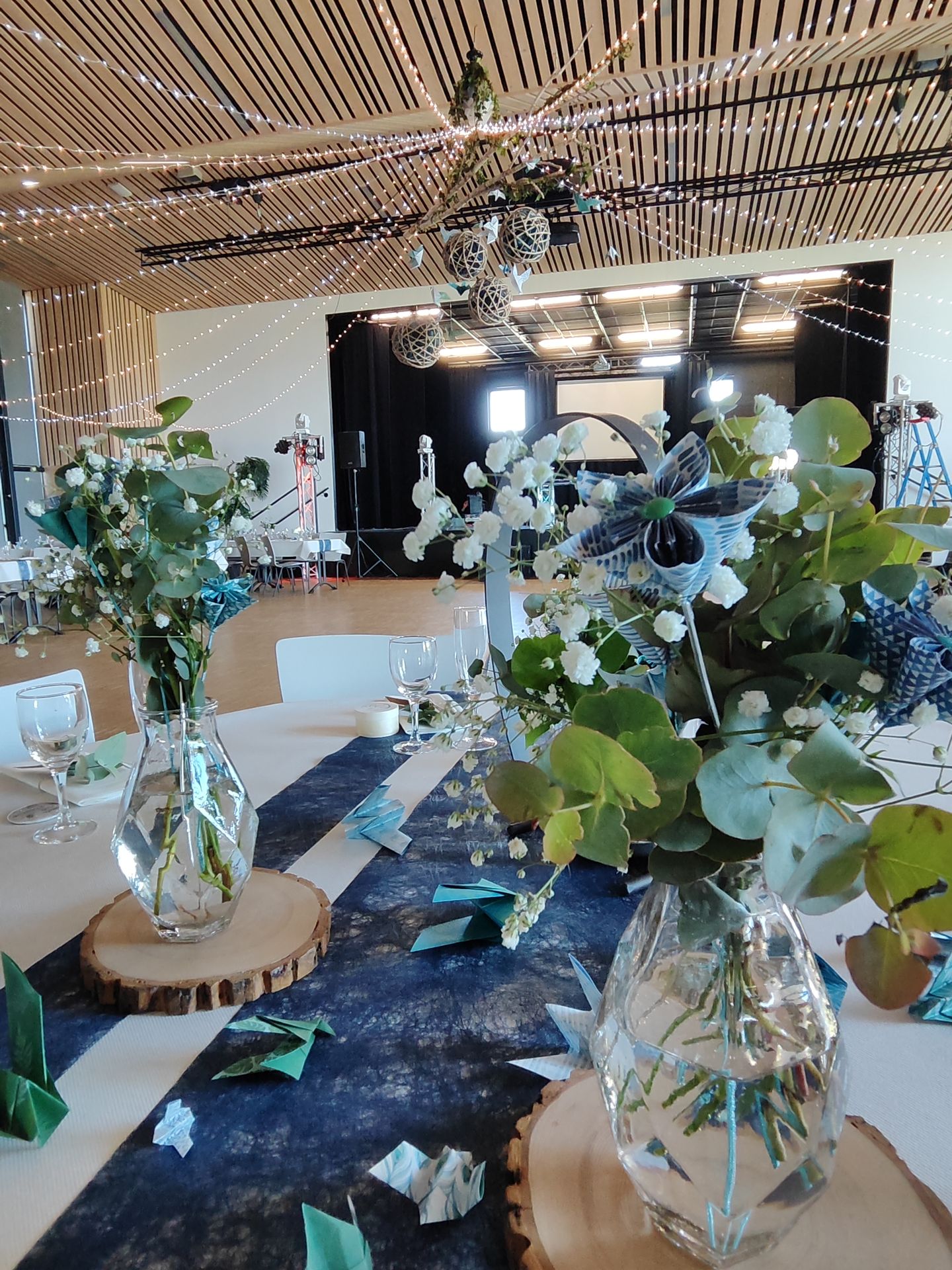 Mariage La Prairie vase transparent composition florales feuillage fleurs bleu rondin en bois coeur argent