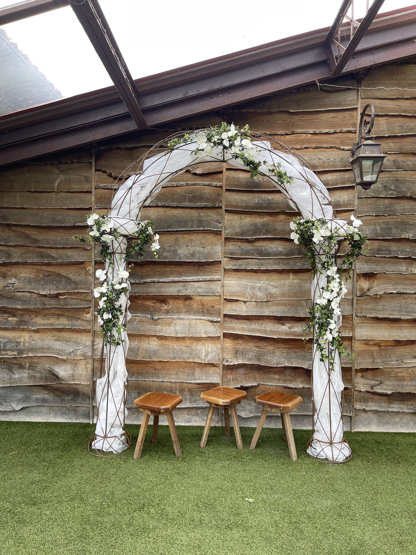 Mariage Vallée de la Roche arche arrondi tissu blanc composition florales tabouret en bois