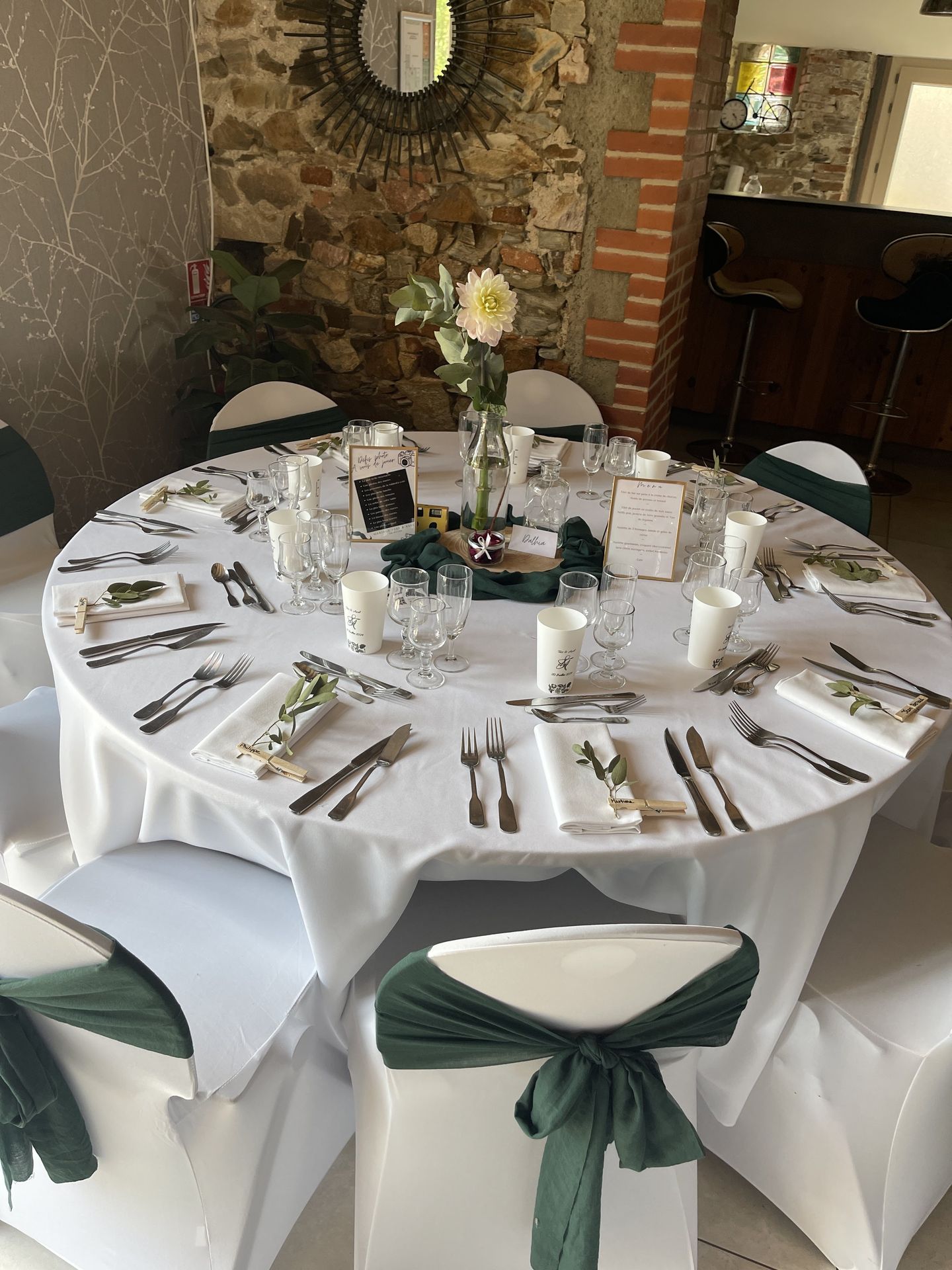 Mariage Domaine de Marin salle intérieure table et chaise blanche noeud vert sapin ciel centre de table tissu vert sapin rondin en bois vase fleurs cadre dorée menu de tabl