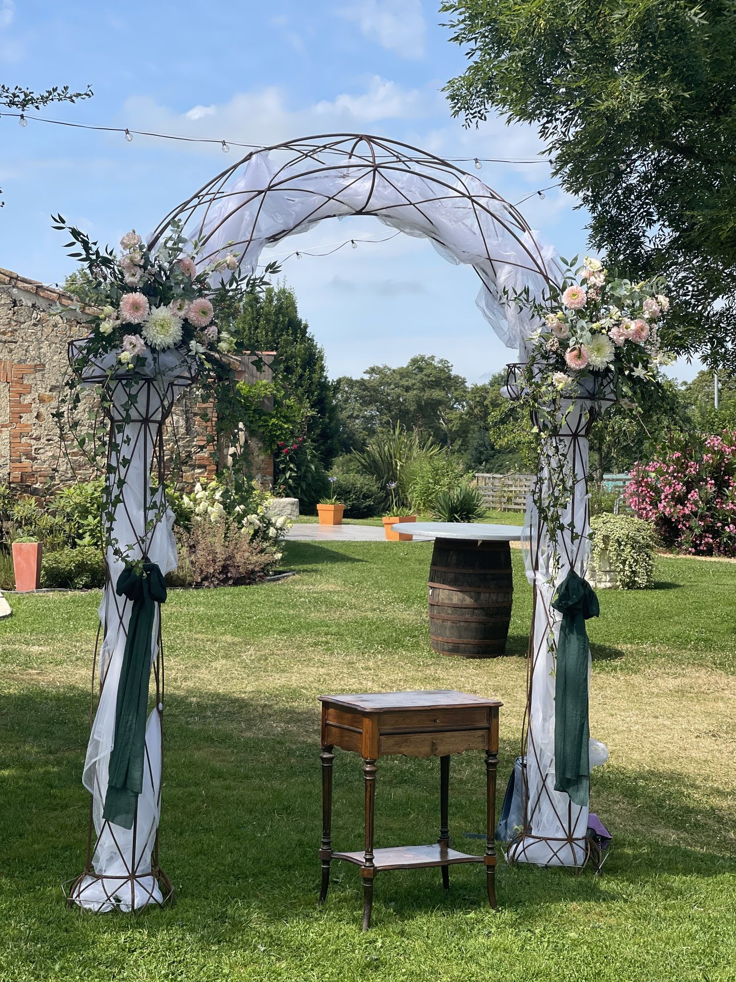 Mariage Domaine de Marin arche arrondi tissu blanc noeud vert sapin composition florales