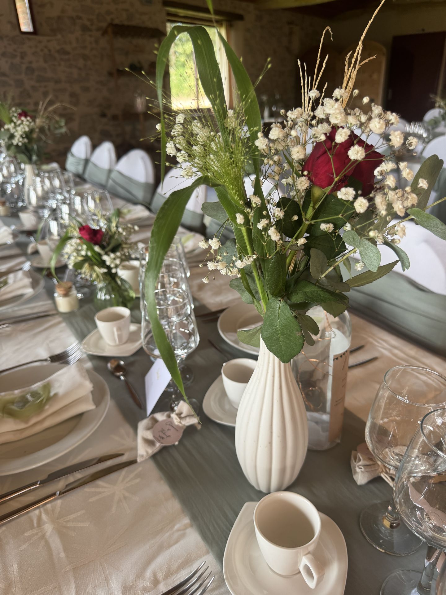 Mariage La Chaumerie table blanche et noeud vert sauge fleurs en vase bougie personnalisé éprouvette menu sur bouteille