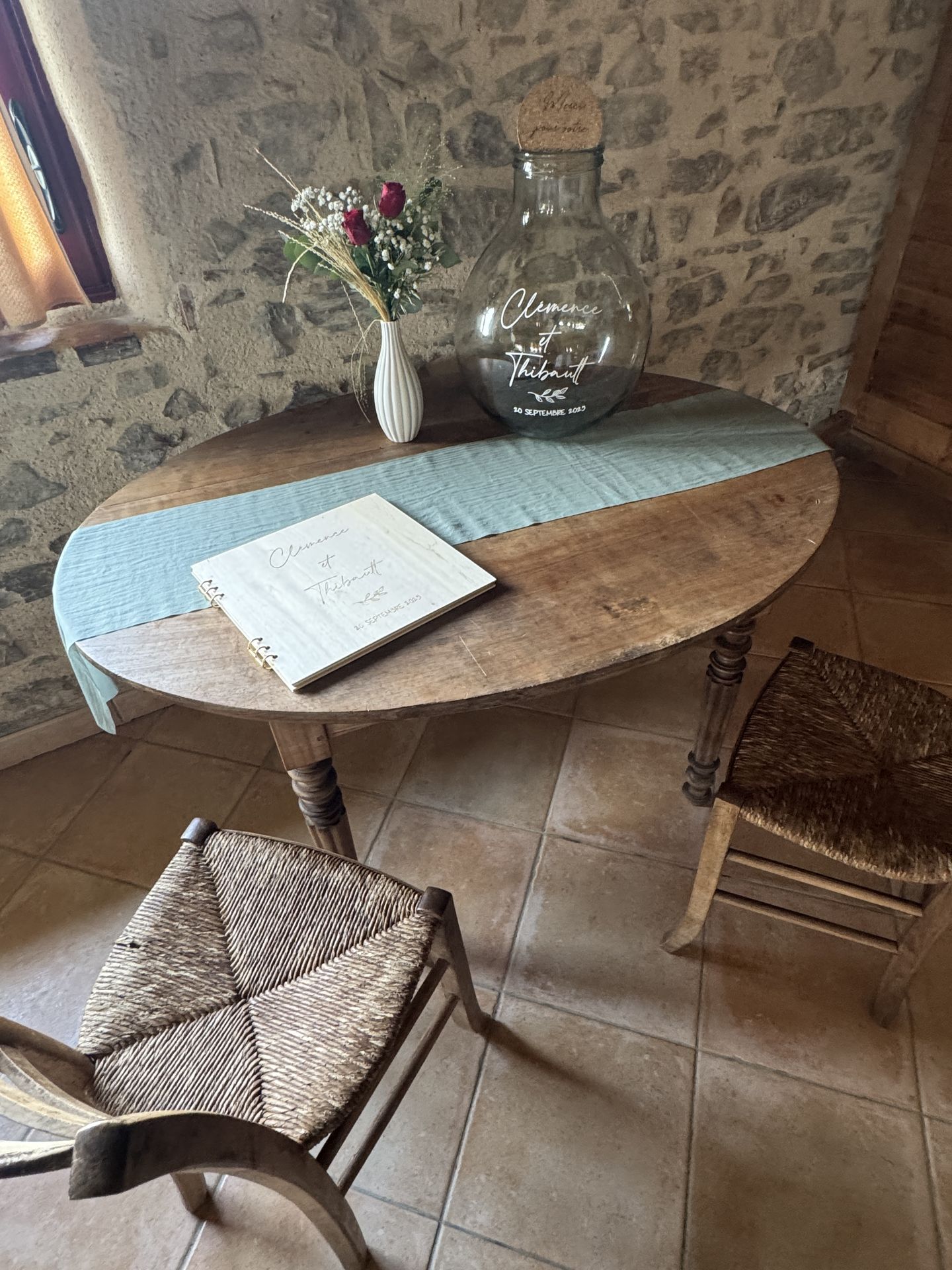 Mariage La Chaumerie espace cagnotte table en bois chemin vert sauge vase blanc fleurs rouge et blanc dame-jeanne personnalisé et livre d'or