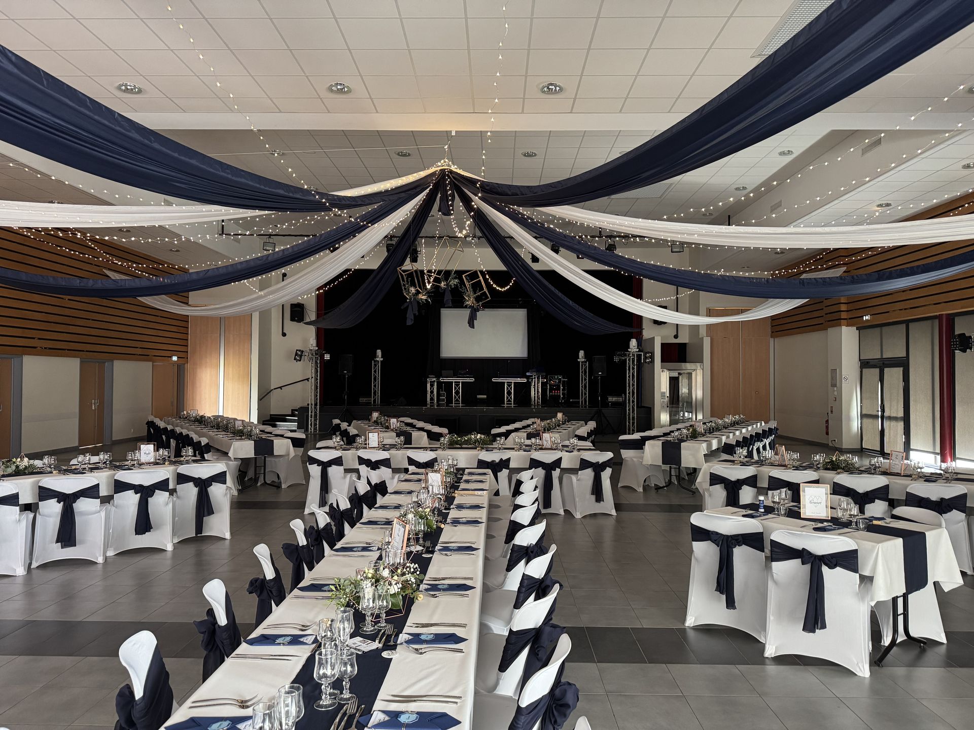 Mariage Espace Galerne plafond tentures bleu et blanc leds structures dorée feuillage table blanche bleu marine noeud de chaise