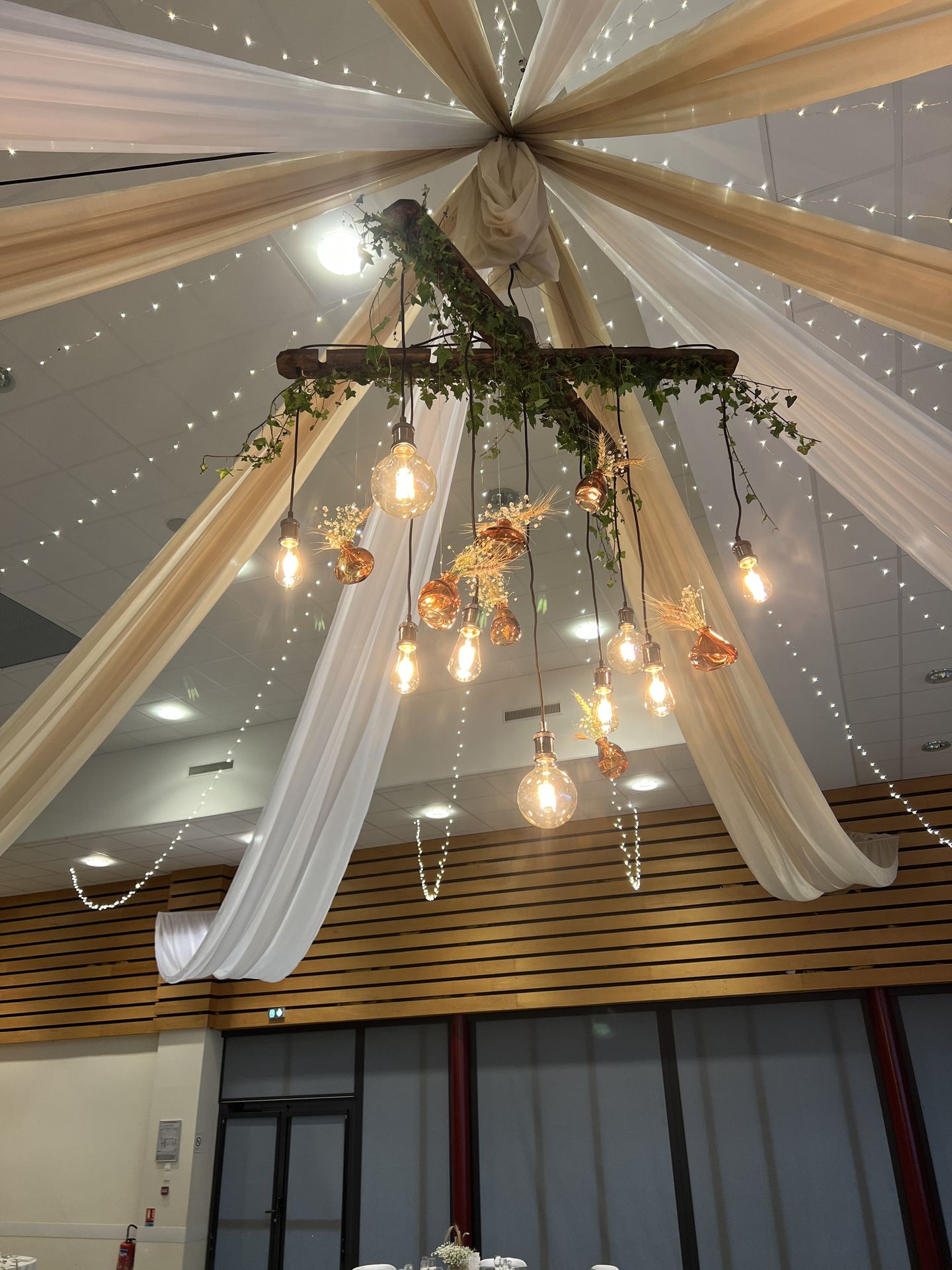 Mariage Espace Galerne plafond tentures blanches et sables structures bois feuillage et ampoules guinguette et vase pampas