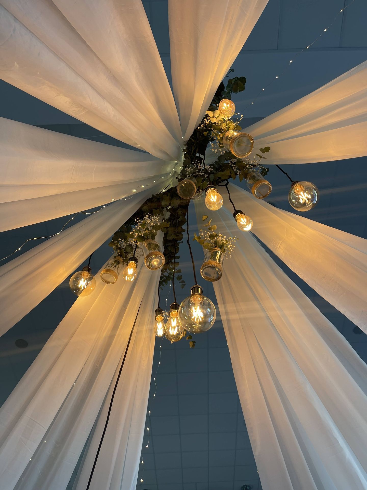 Mariage Espace Galerne plafond tentures blanches leds et structure bois feuillage ampoule guinguette et vase fleuris