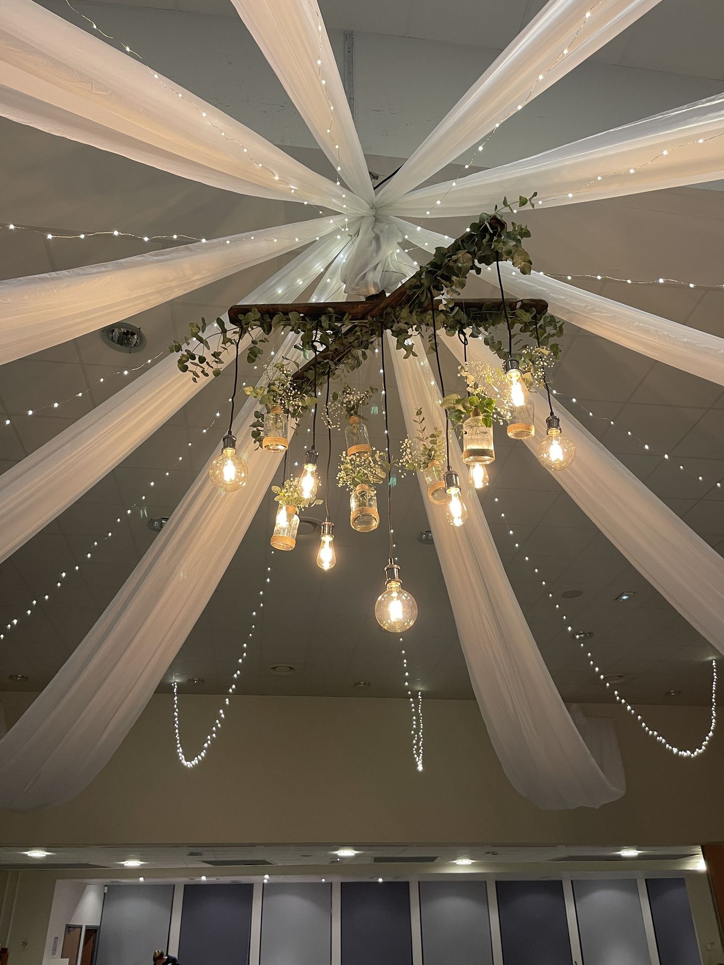 Mariage Espace Galerne plafond tentures blanches leds et structure bois feuillage ampoule guinguette et vase fleuris