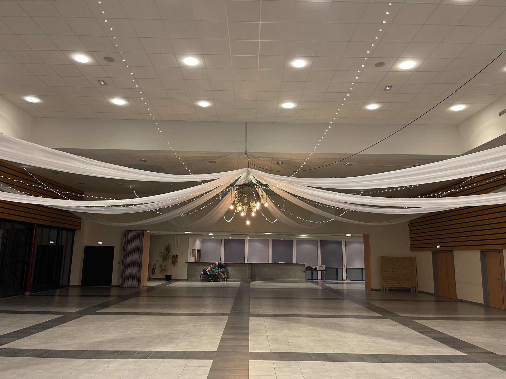 Mariage Espace Galerne plafond tentures blanches leds et structure bois feuillage ampoule guinguette et vase fleuris