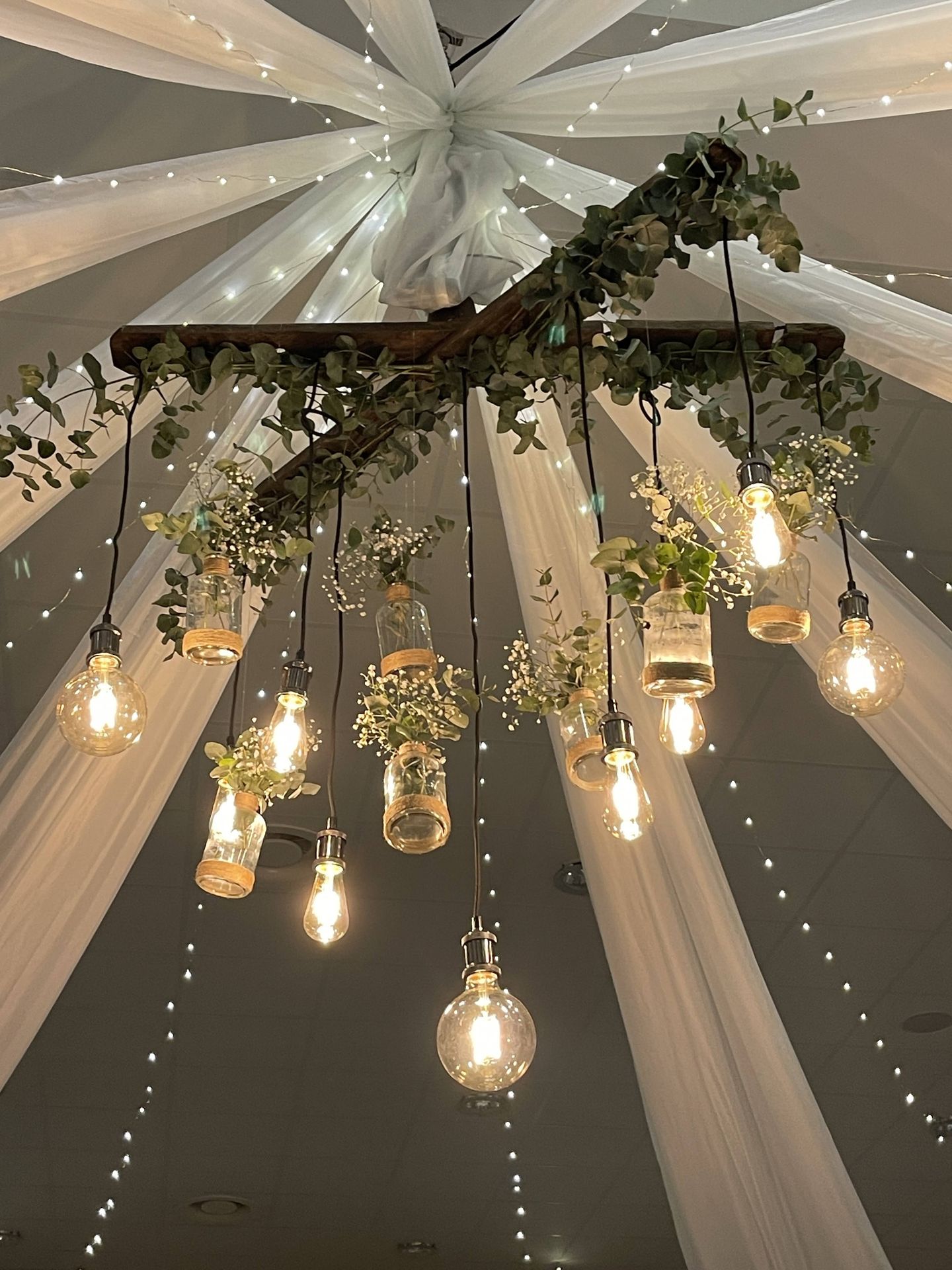 Mariage Espace Galerne plafond tentures blanches leds et structure bois feuillage ampoule guinguette et vase fleuris