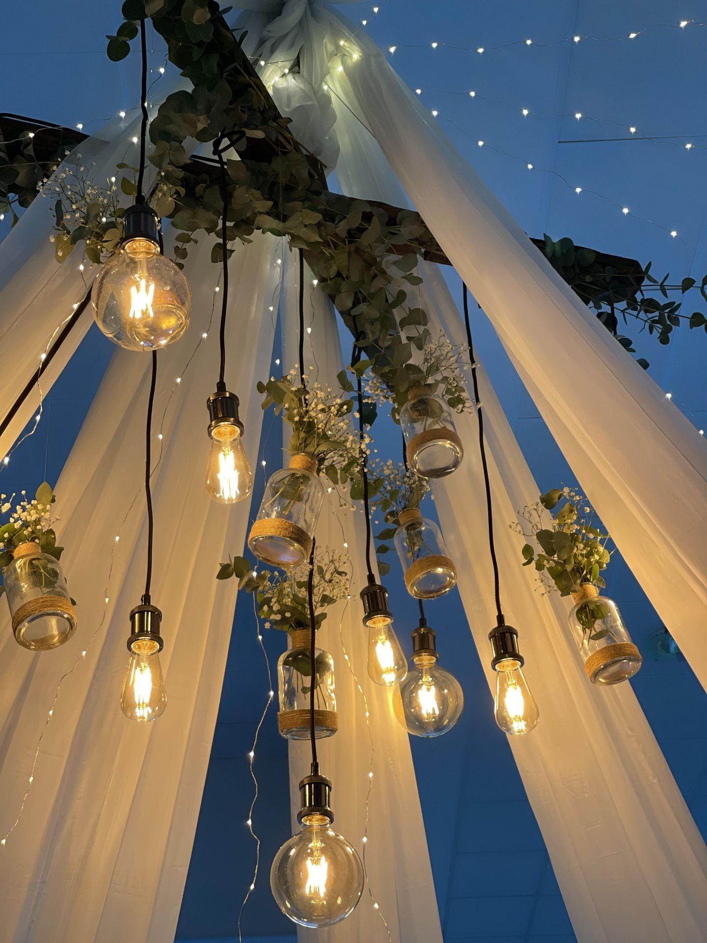 Mariage Espace Galerne plafond tentures blanches leds et structure bois feuillage ampoule guinguette et vase fleuris
