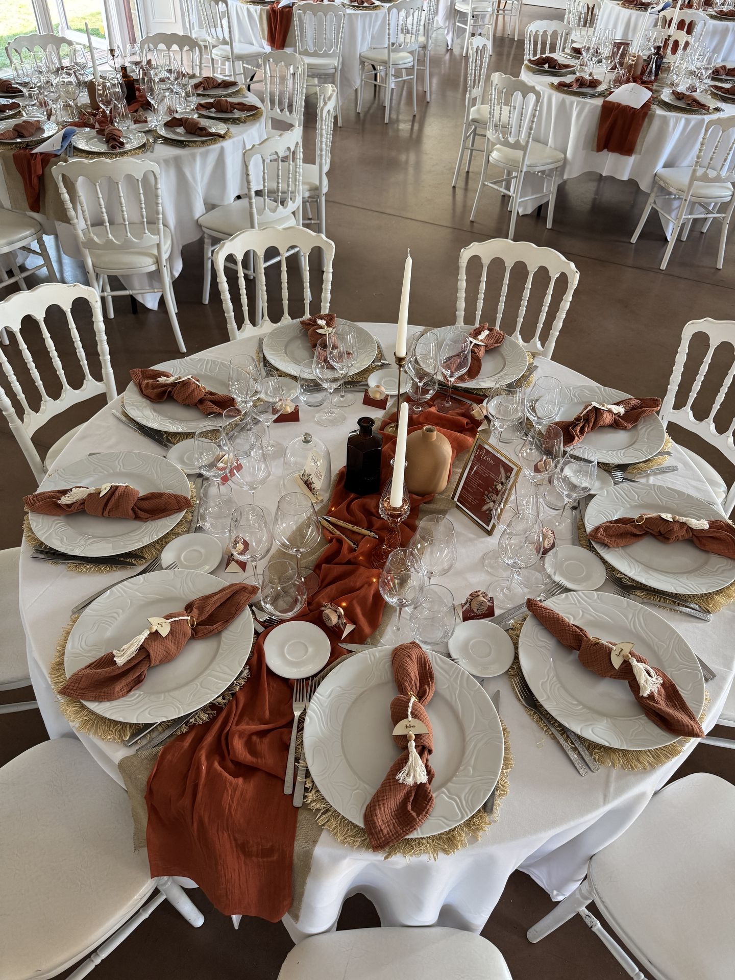 Mariage Domaine de la Jousselinière salle intérieure table blanche serviette terracotta chemin de table sable et terracotta bougie vase naturel