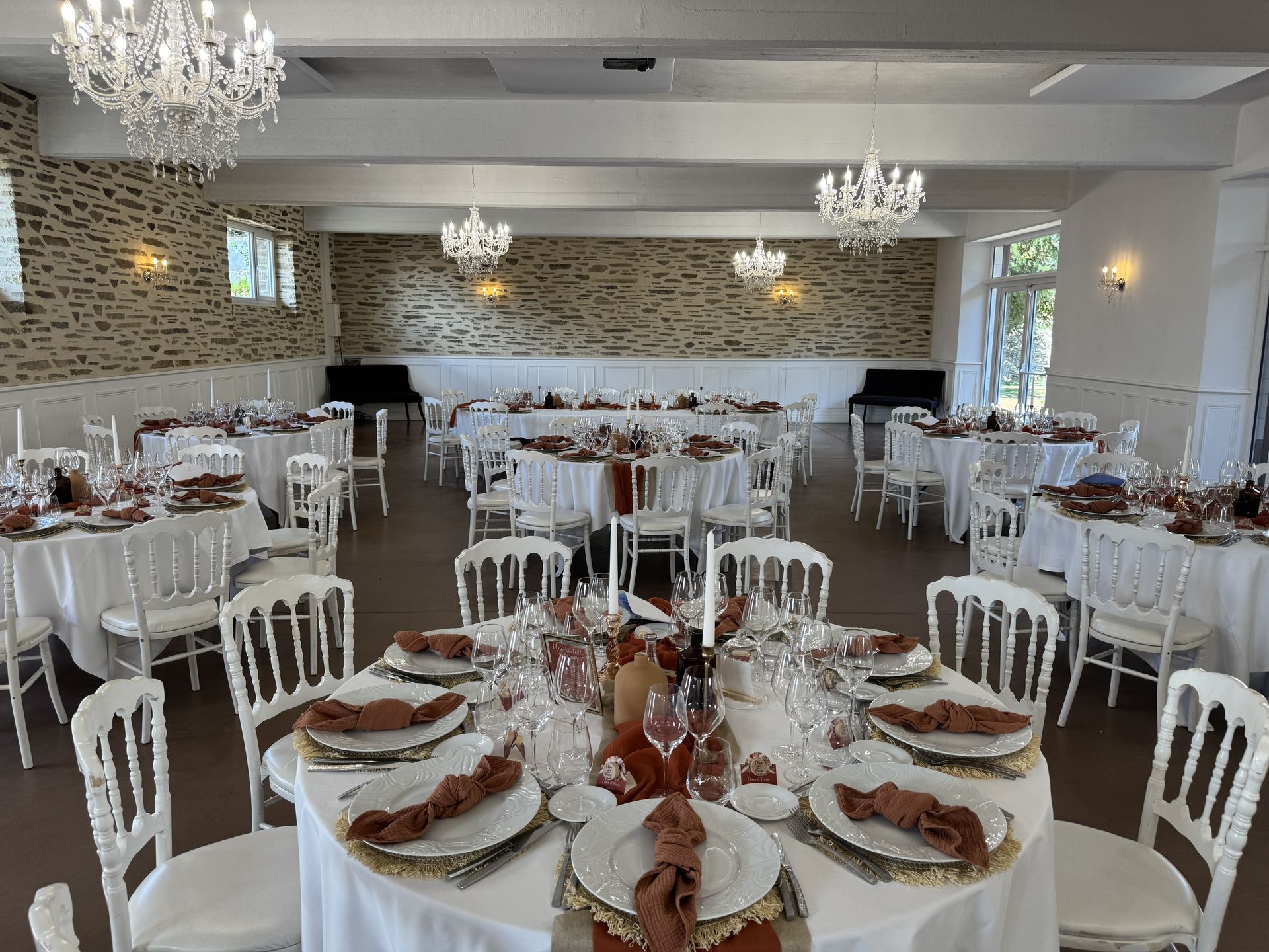 Mariage Domaine de la Jousselinière salle intérieure table blanche serviette terracotta chemin de table sable et terracotta bougie vase naturel