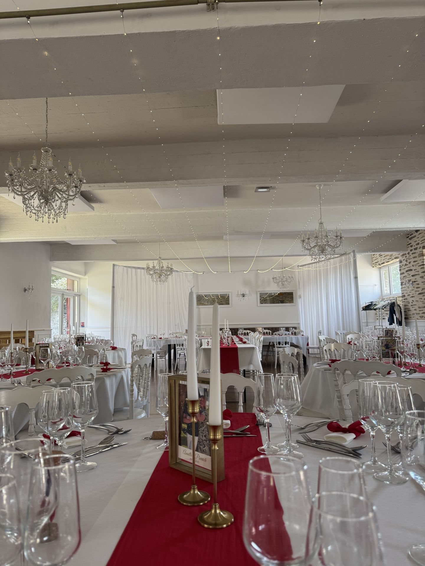 Mariage Domaine de la Jousselinière salle intérieure plafond ciel étoilé table blanche chemin de table rouge bougie blanche cadre dorée noeud rouge