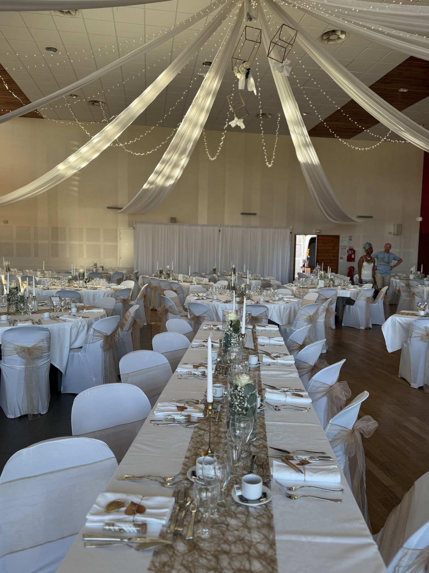 Mariage Espace Convivial plafond tentures blanches et leds tables blanches noeud de chaise dorée