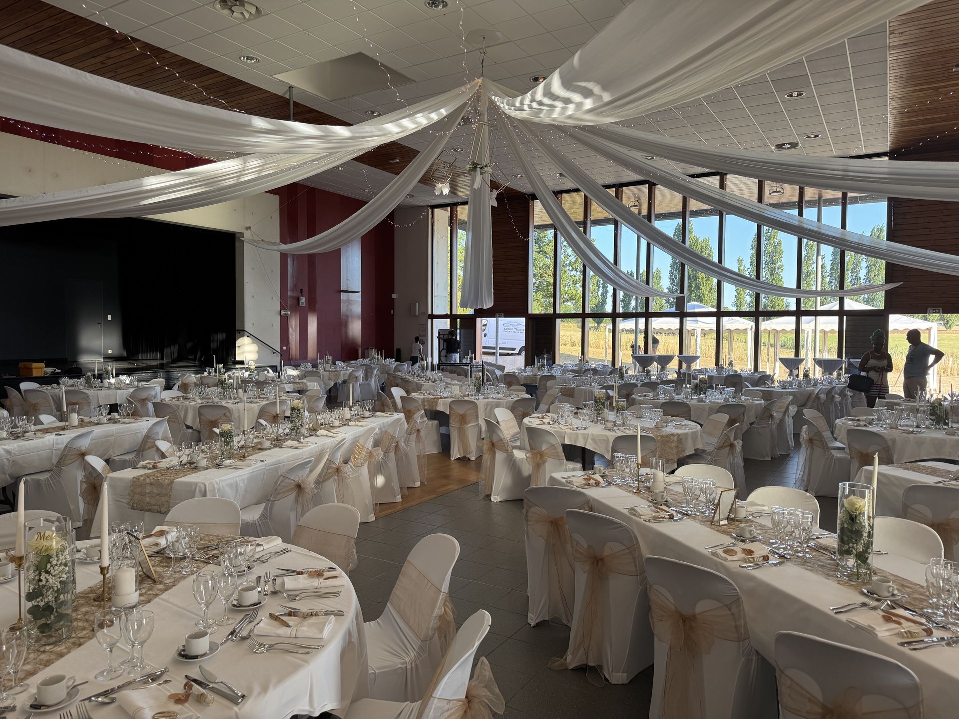 Mariage Espace Convivial plafond tentures blanches et leds tables blanches noeud de chaise dorée
