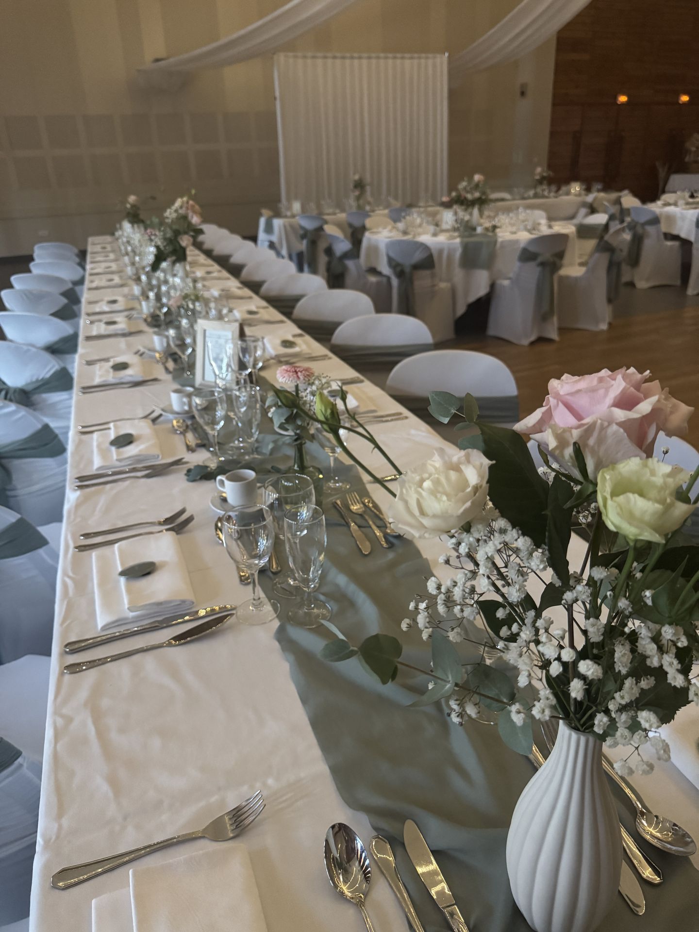 Mariage Espace convivial table blanche chemin de table vert sauge vase fleuris nom de table cadre en bois