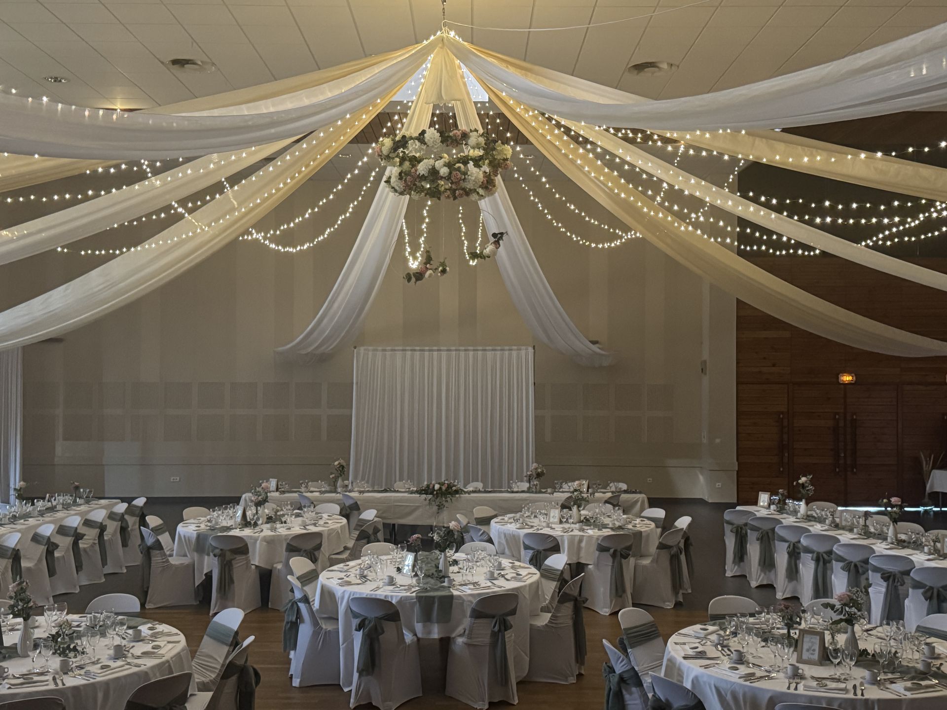Mariage Espace convivial plafond tentures blanches sables lleds couronnes de fleurs table blanche vert sauge