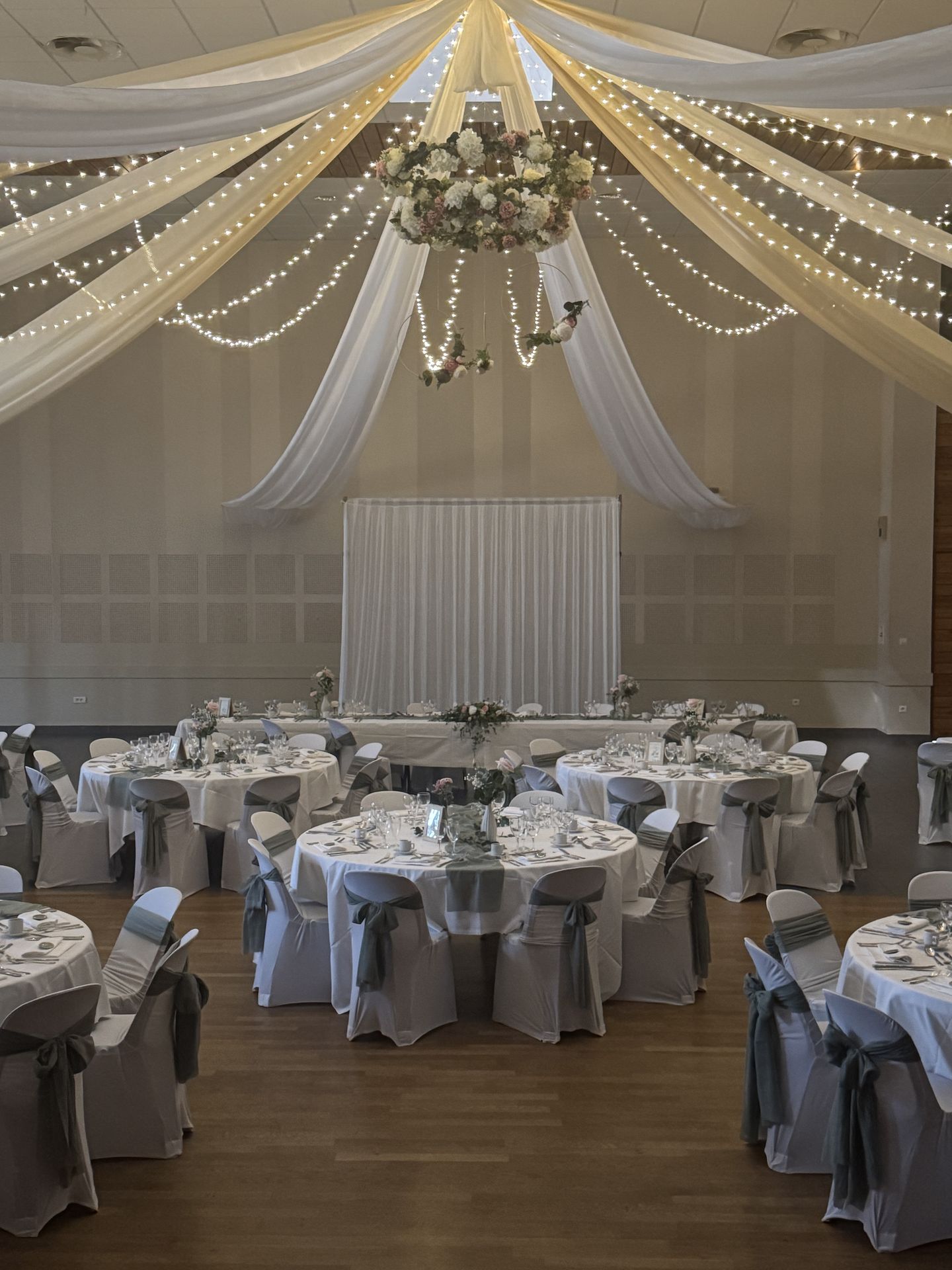Mariage Espace convivial plafond tentures blanches sables lleds couronnes de fleurs table blanche vert sauge